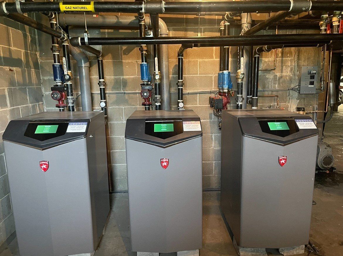 Trois chaudières sont placées côte à côte dans un sous-sol.