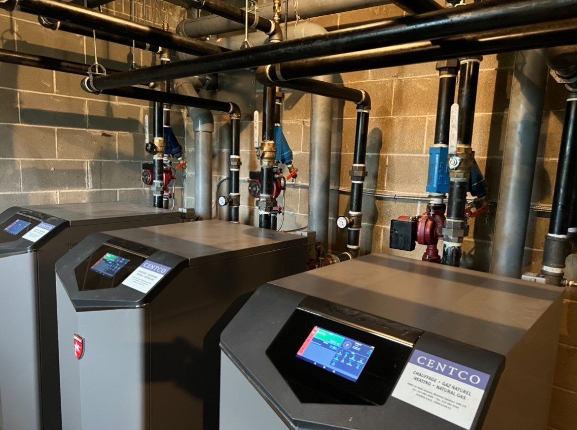 Deux chauffe-eau sont assis l'un à côté de l'autre dans une pièce avec des tuyaux.