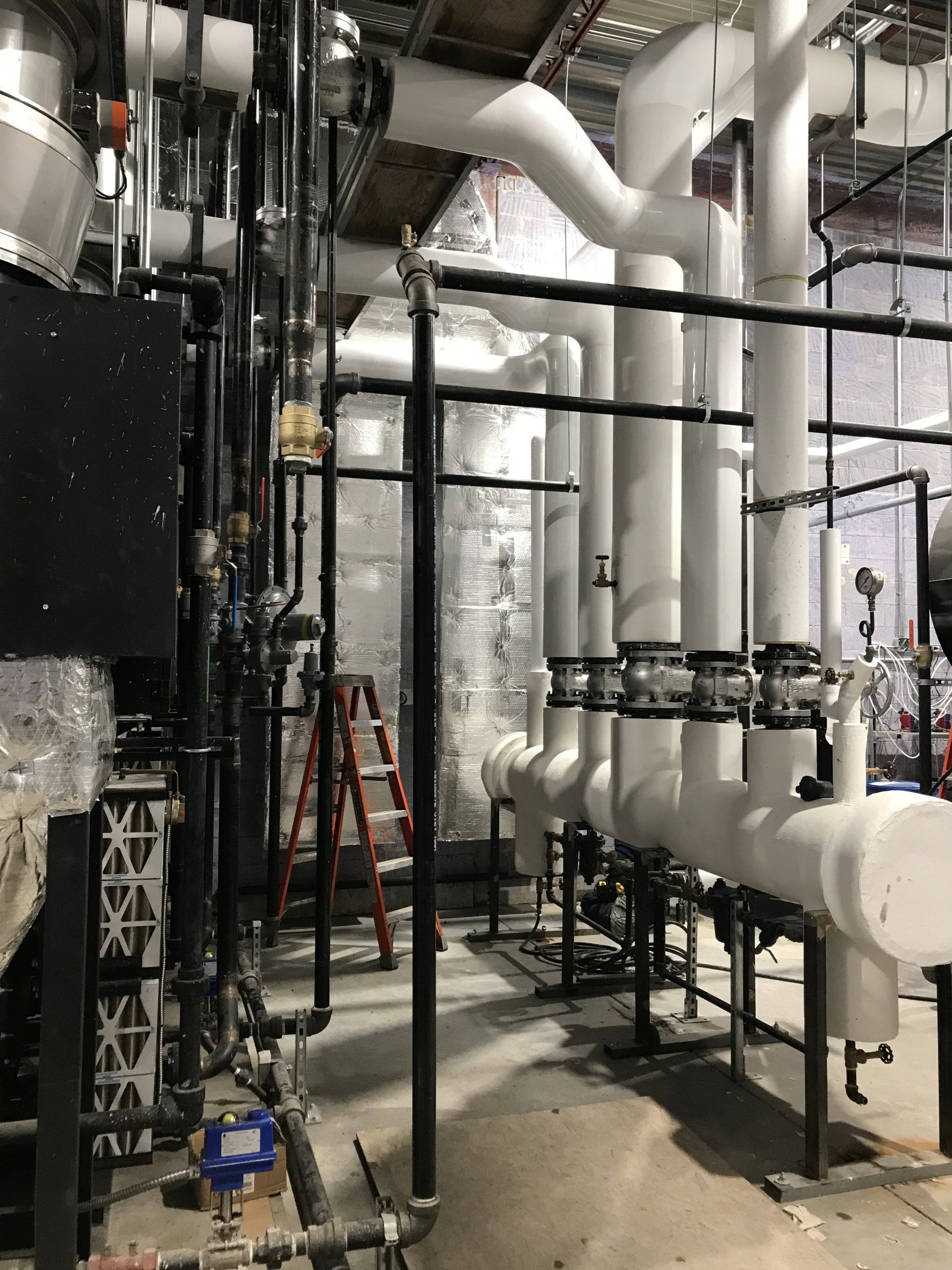 Une pièce remplie de nombreux tuyaux et d'une échelle.