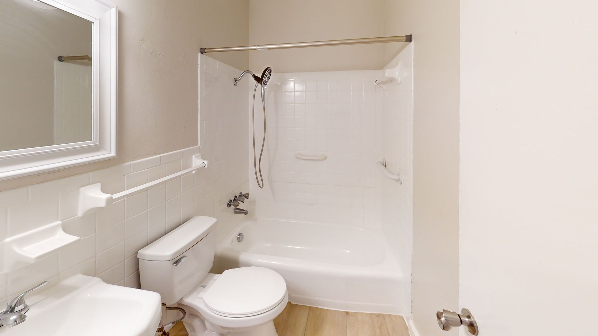 A bathroom with a toilet , sink , shower and mirror.