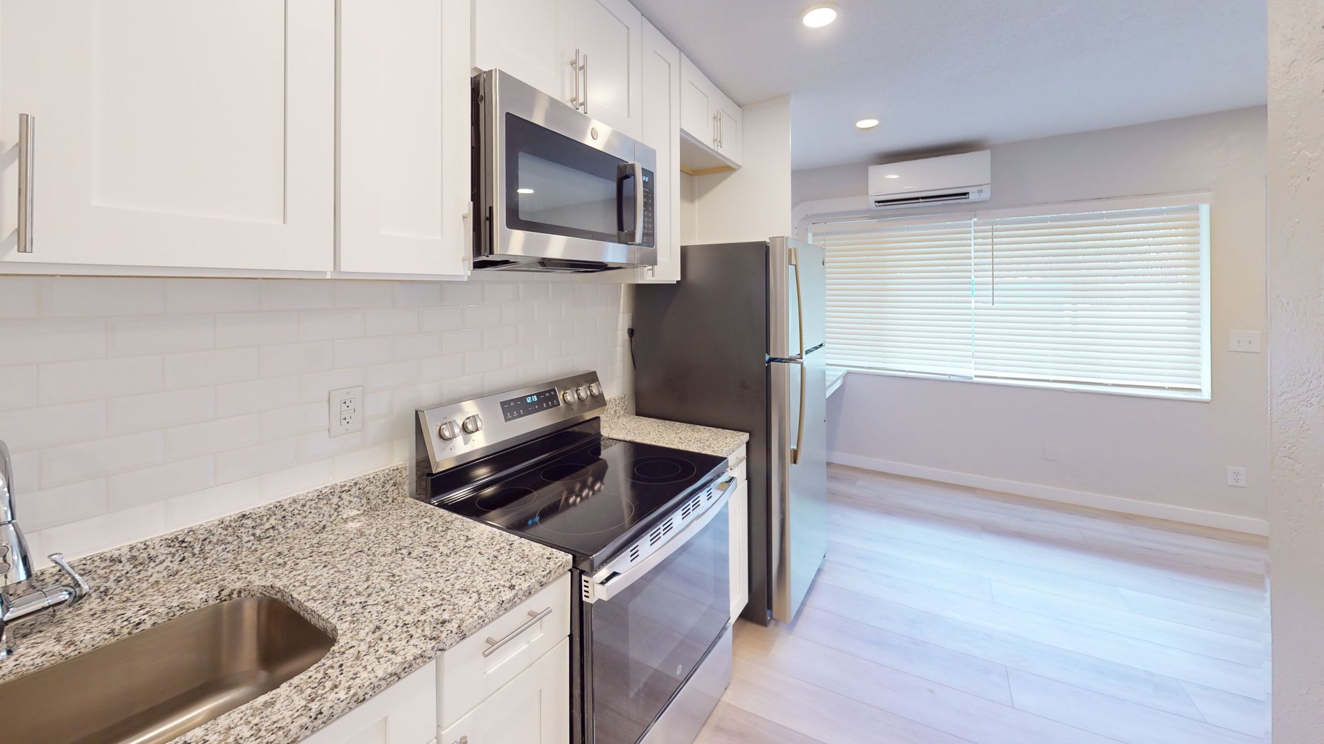 A kitchen with a stove , sink , refrigerator and microwave.