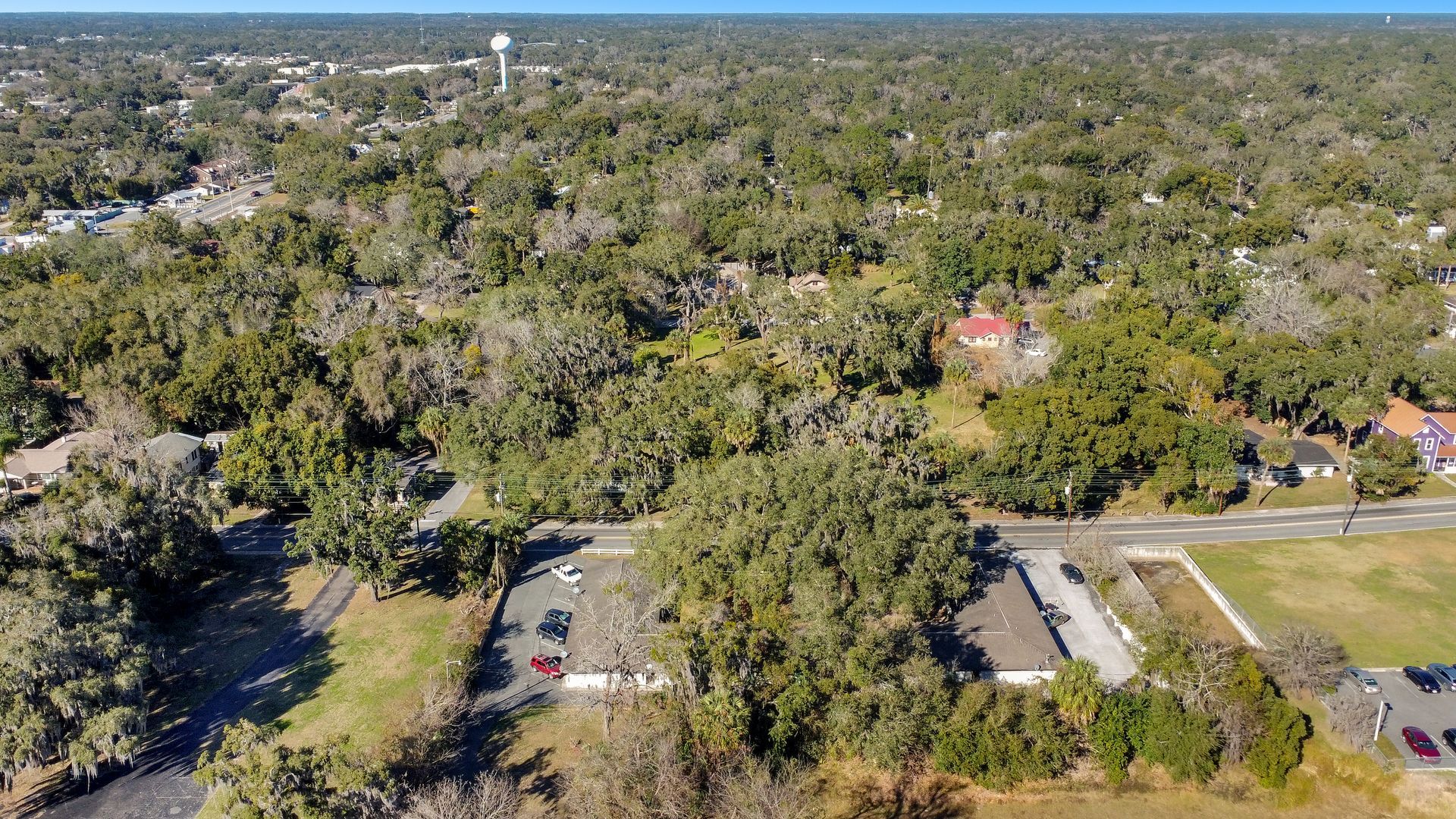 An aerial view of a residential area surrounded by trees and a parking lot.