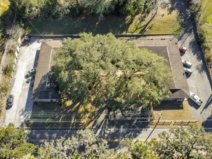 An aerial view of a house surrounded by trees and a parking lot.