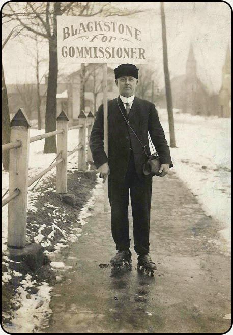 a man stands in front of a sign that says blackstone for commissioner