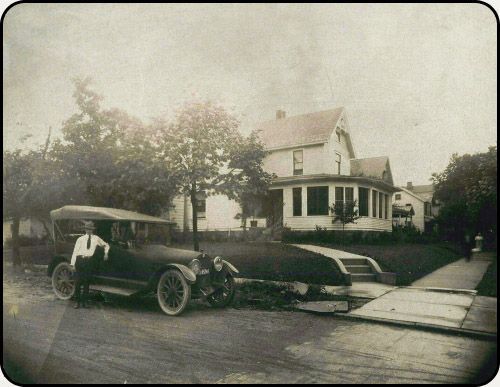 a black and white photo of a car parked in front of a house