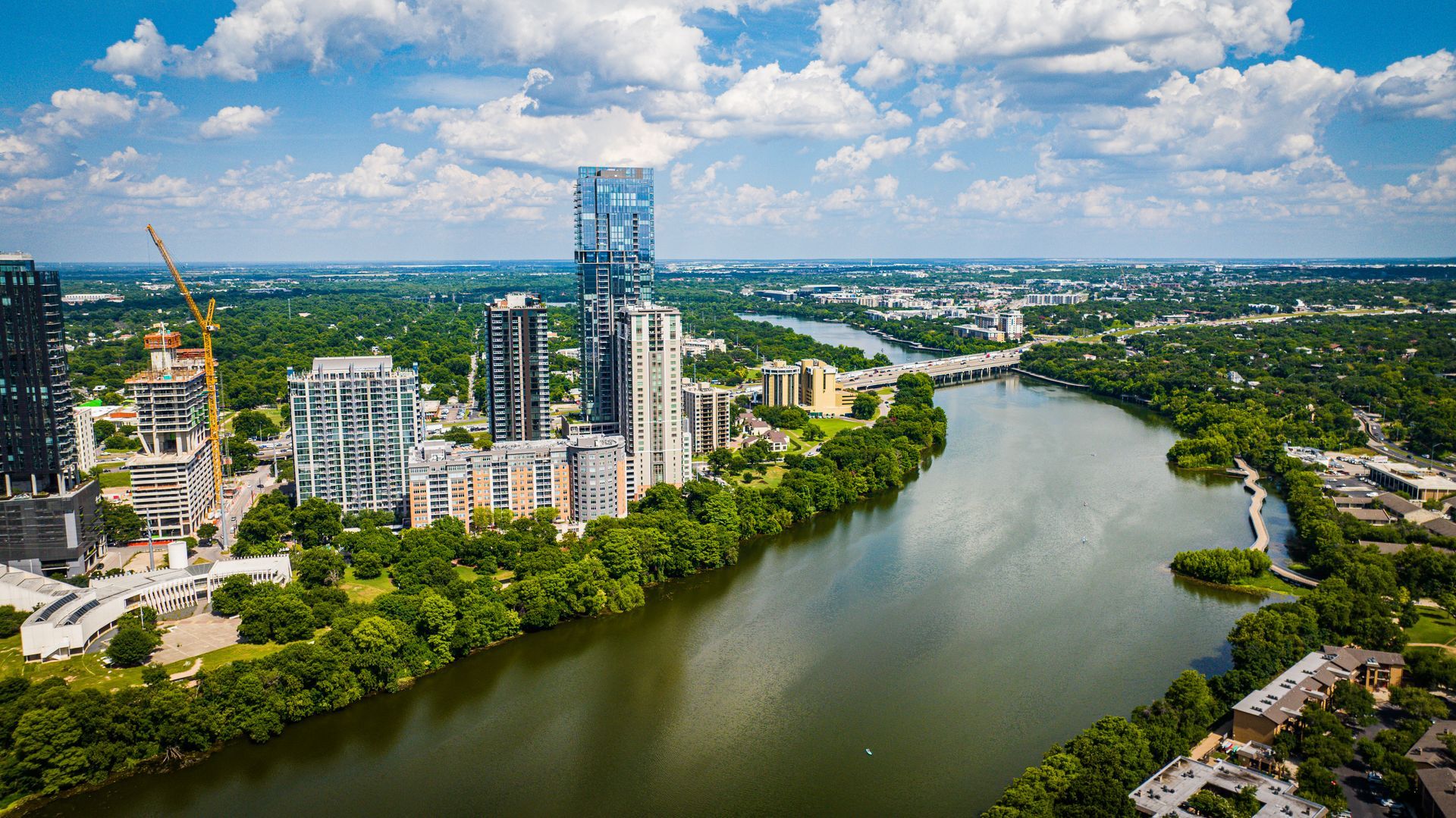 An aerial view of a river surrounded by trees and buildings in a city.