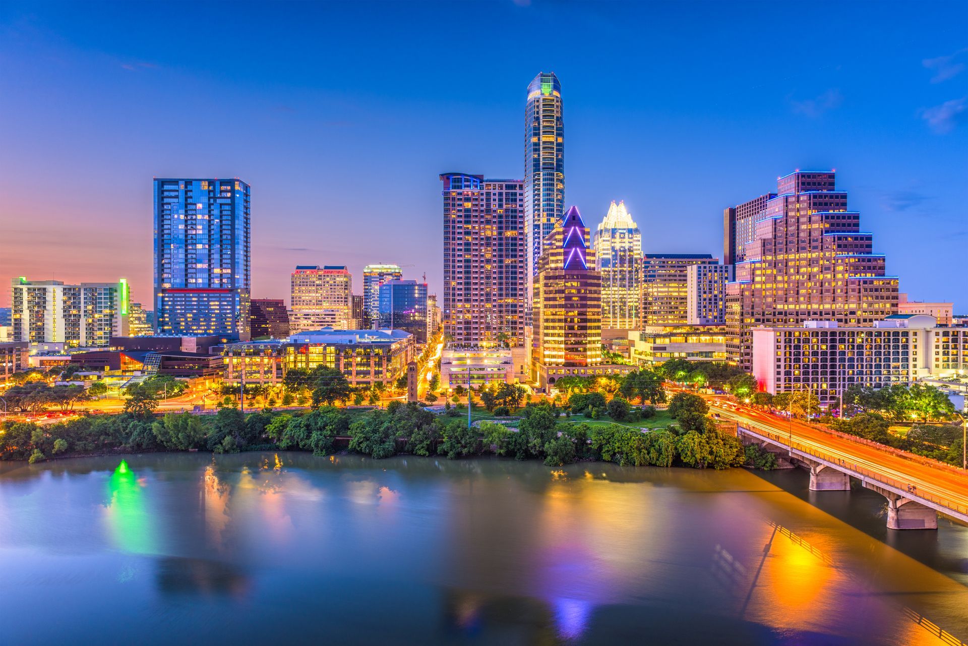 An aerial view of the city skyline at night with a river in the foreground.