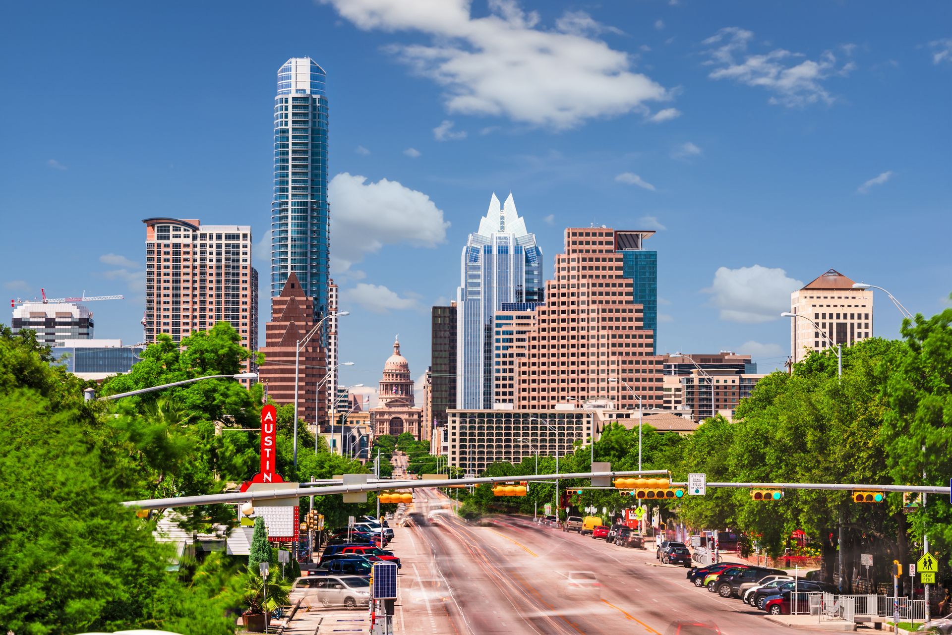 A painting of a city skyline with a street in the foreground.