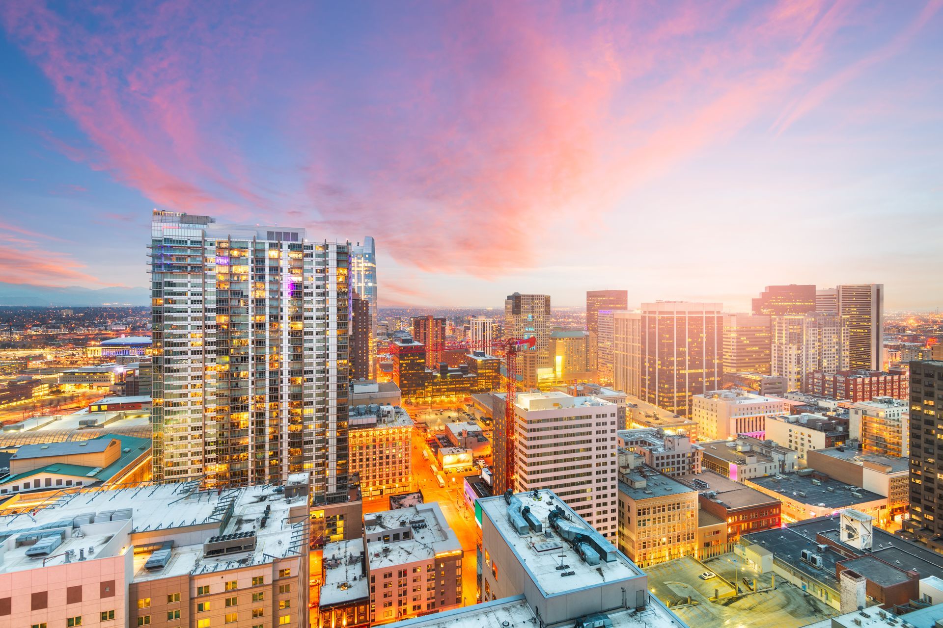 An aerial view of a city at night with a sunset in the background.