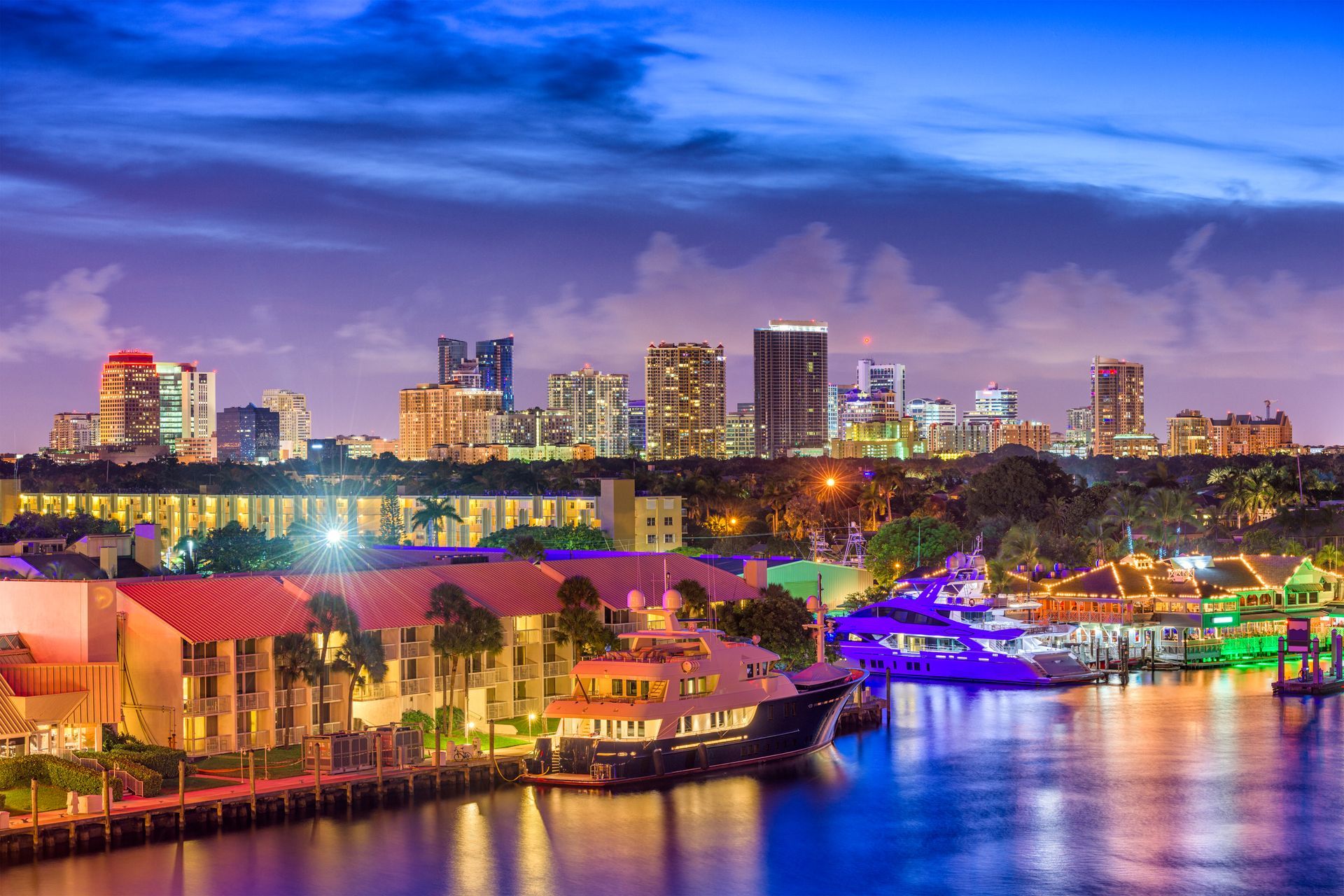 A city skyline at night with a boat in the foreground.