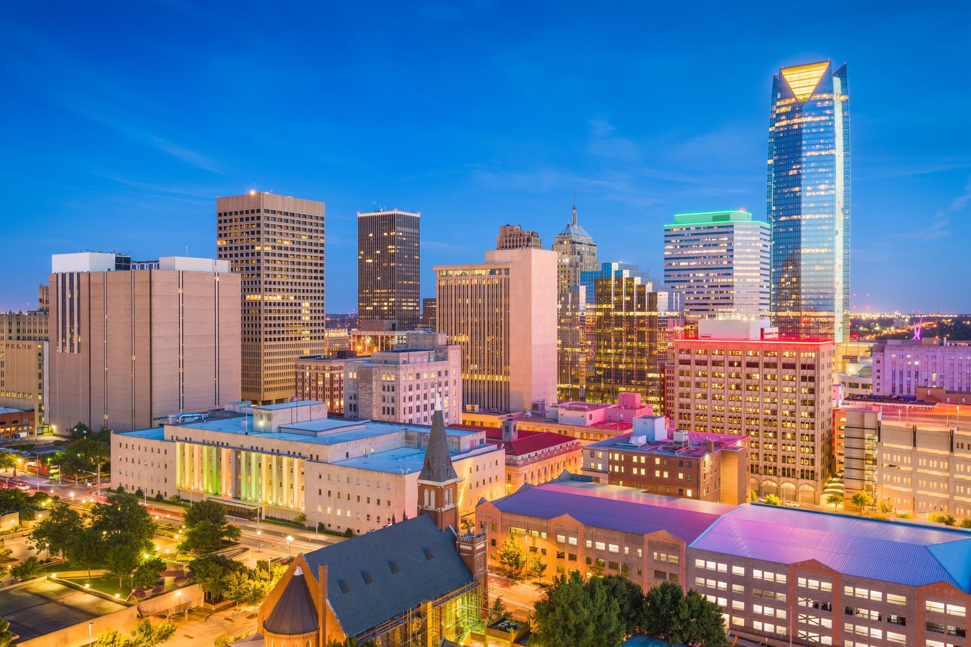 An aerial view of a city skyline at night with a church in the foreground.