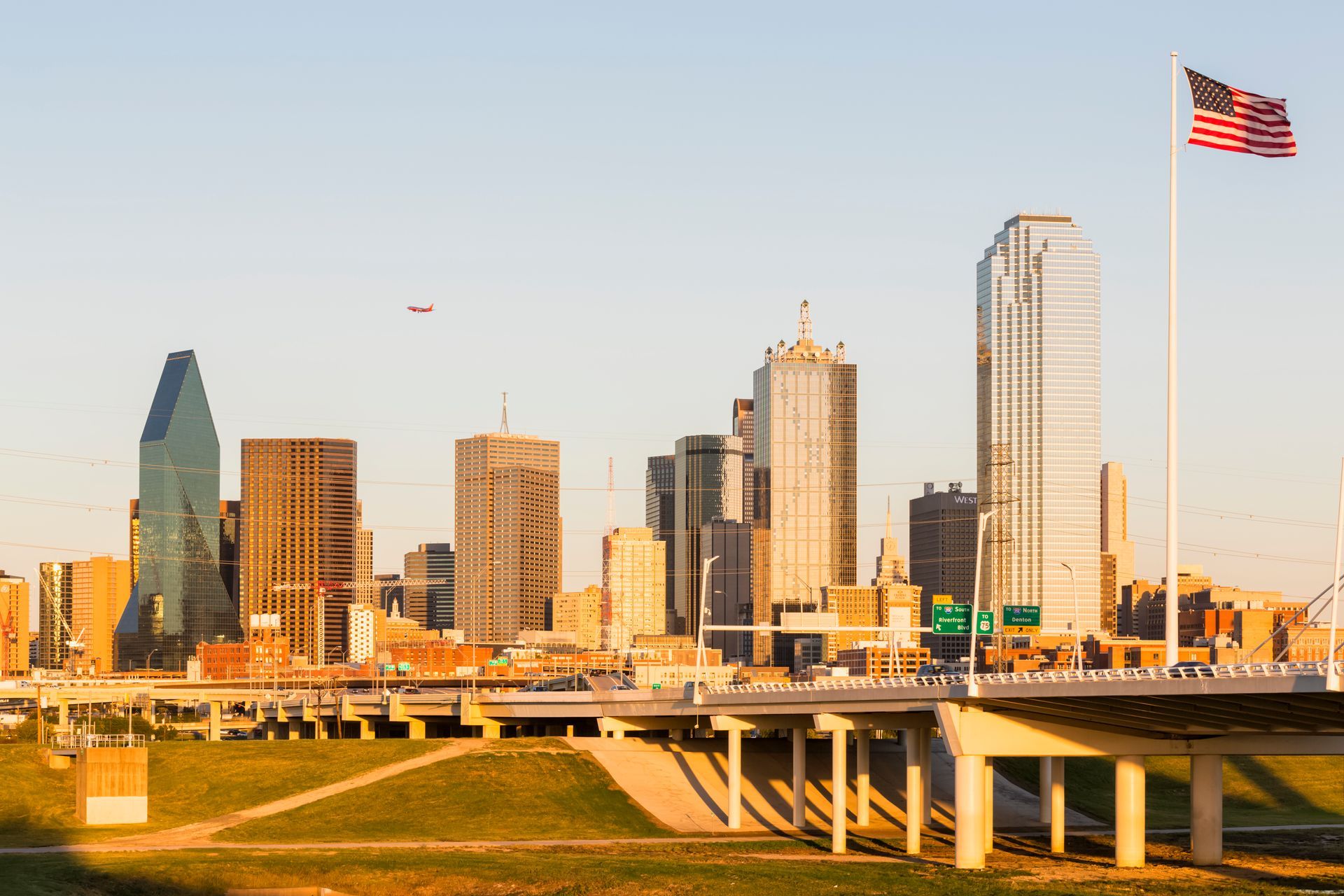 A city skyline with a bridge and an american flag in the foreground.
