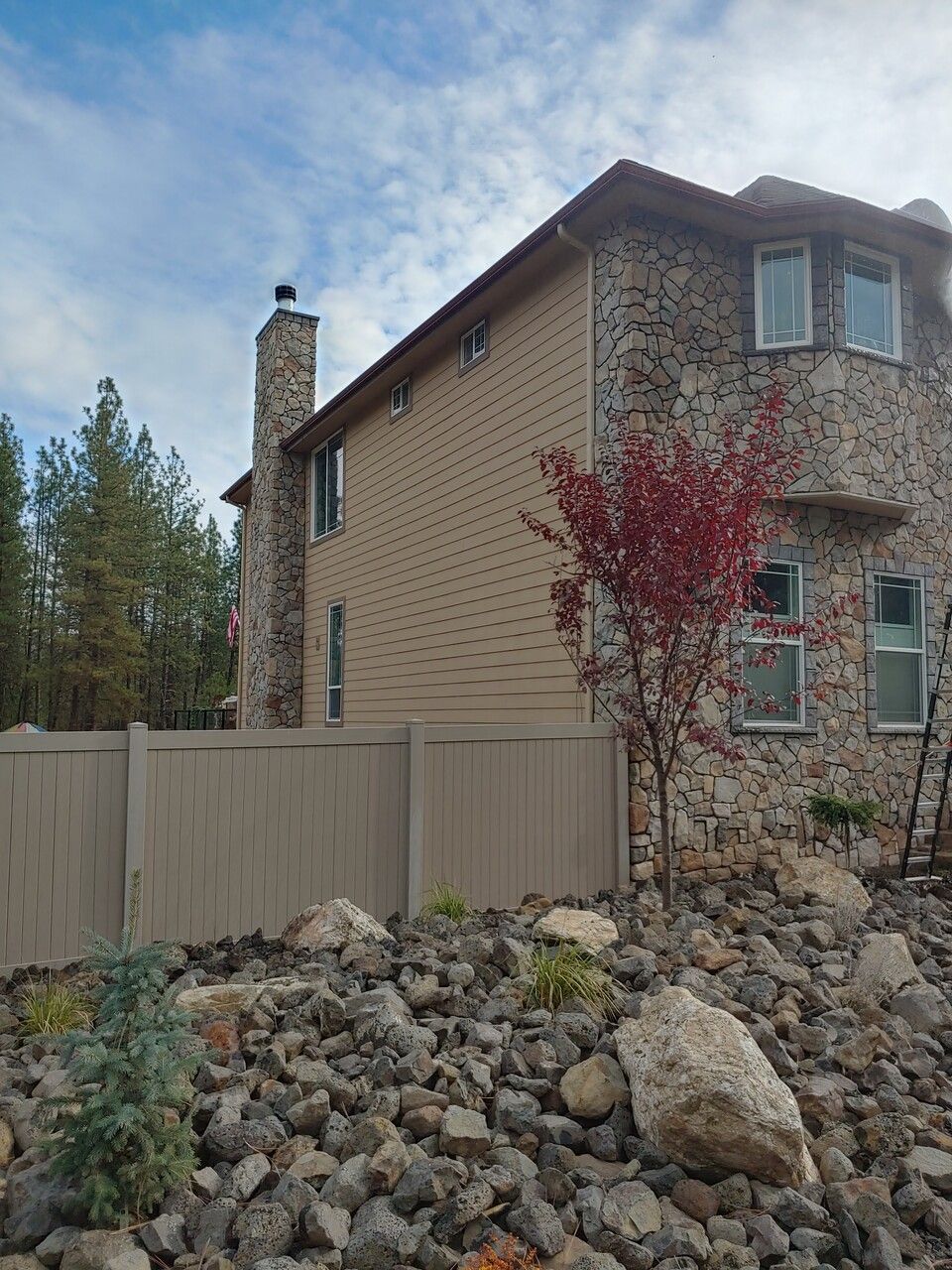 A large stone house with a wooden fence in front of it.