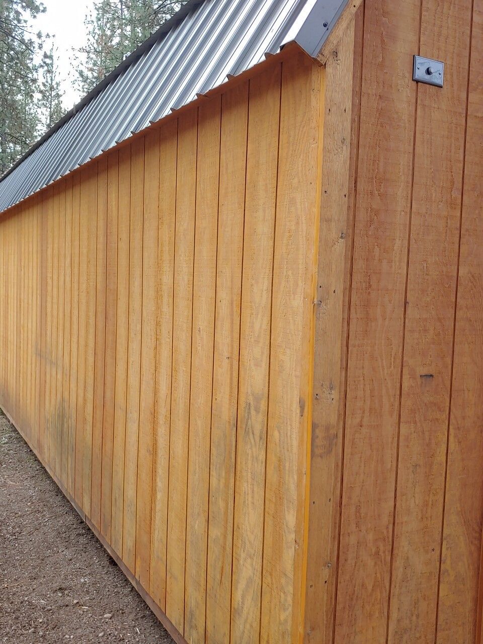 The side of a wooden building with a metal roof
