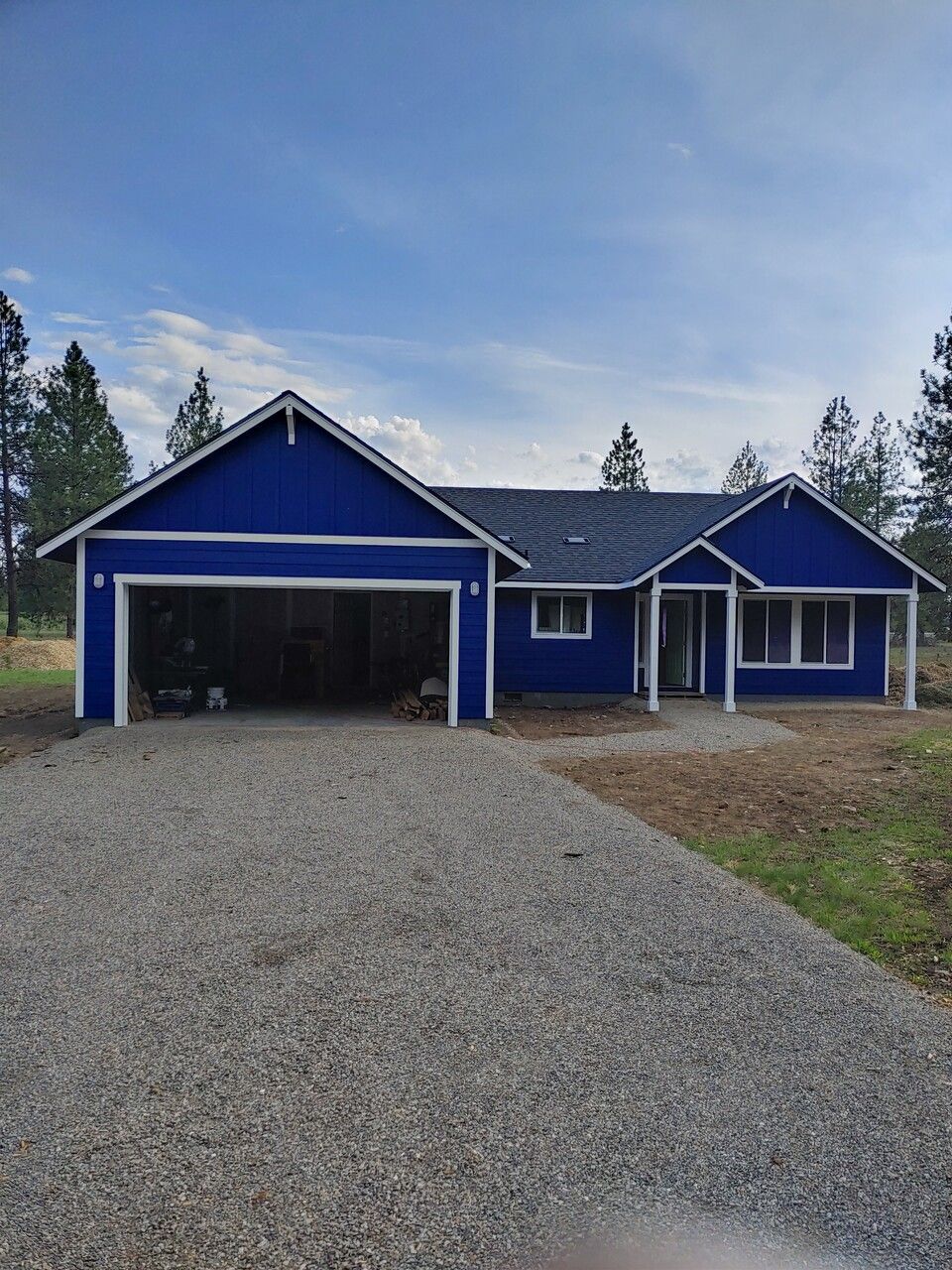 A blue house with a garage and a gravel driveway.