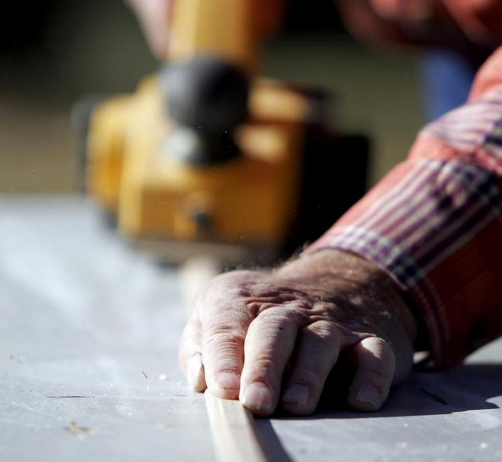 A close up of a person 's hand holding a piece of wood
