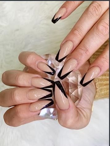 Long, beige nails with sharp black tips, held over a glass prism.