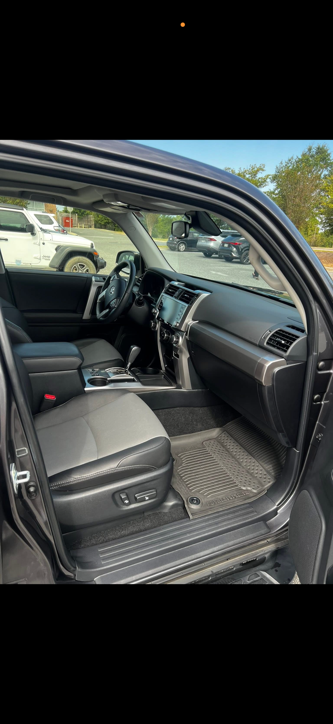 Interior view of a black SUV, showing the driver's side with seats, dashboard, and door open to the outside.
