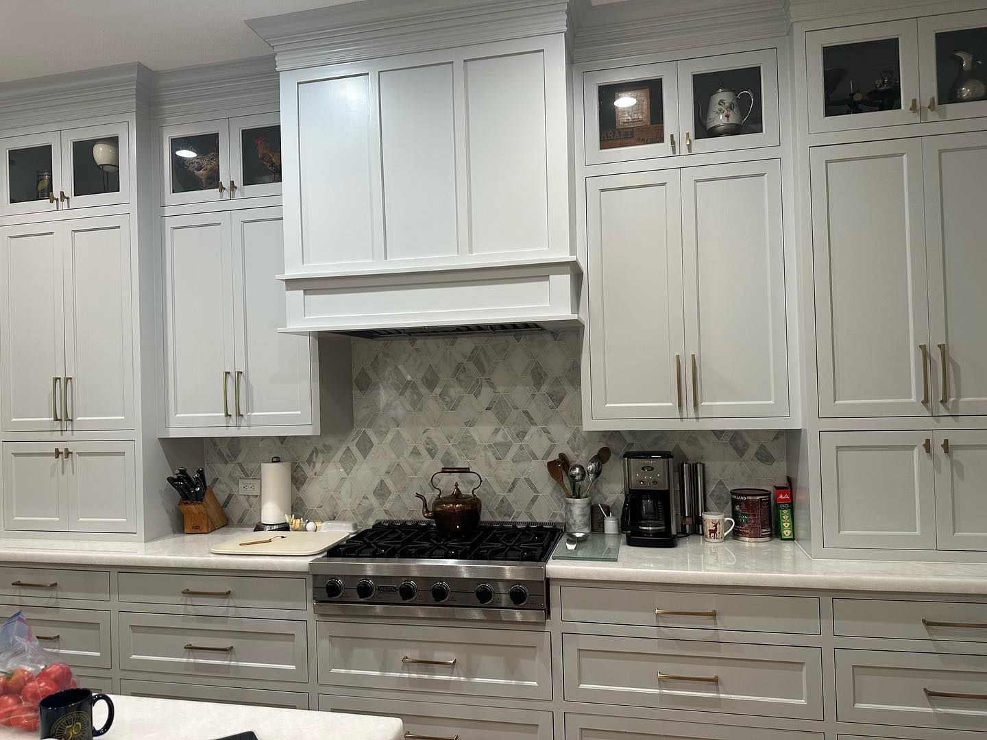 A kitchen with white cabinets and a stove top oven.