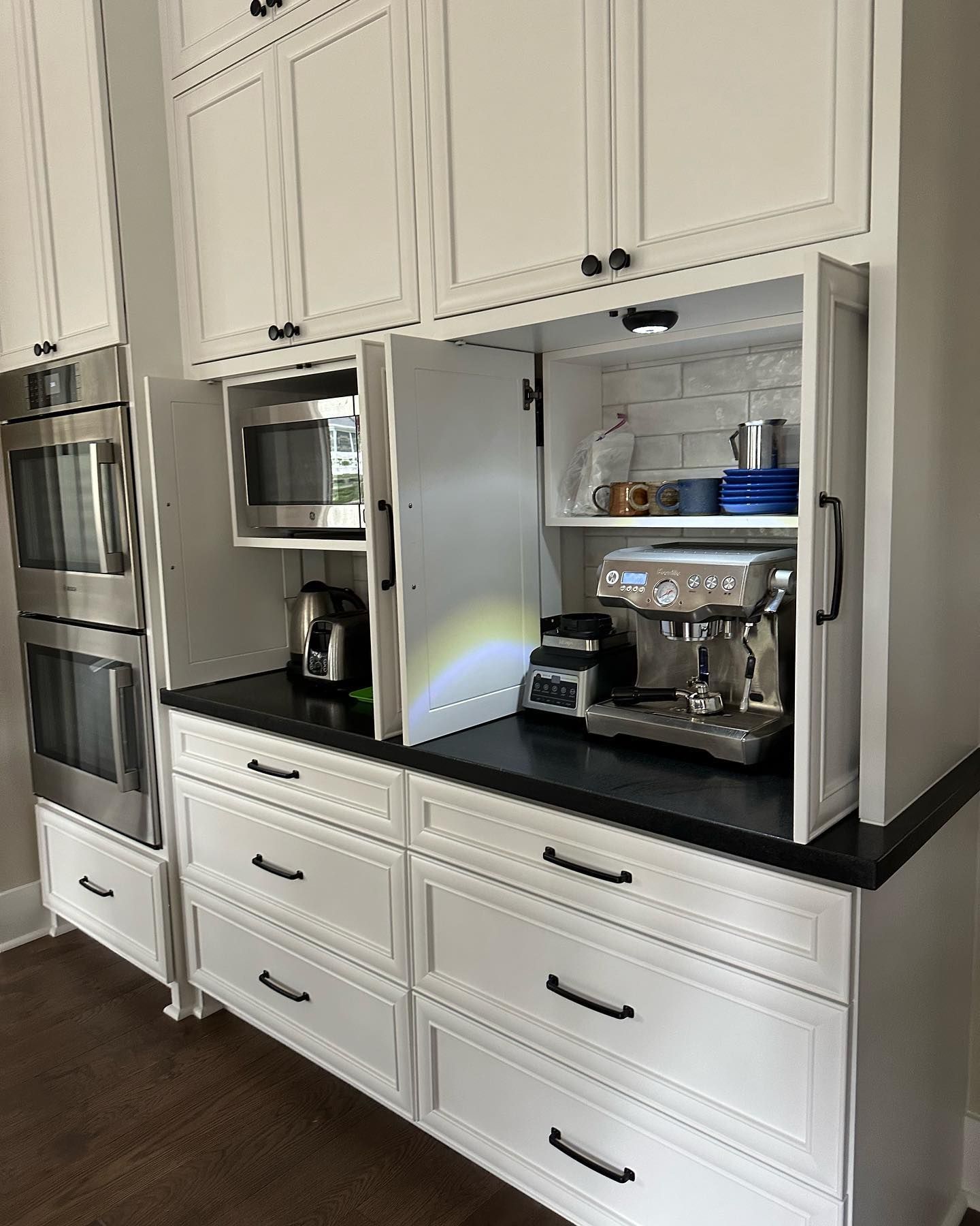 A kitchen with white cabinets , stainless steel appliances , and a coffee maker.