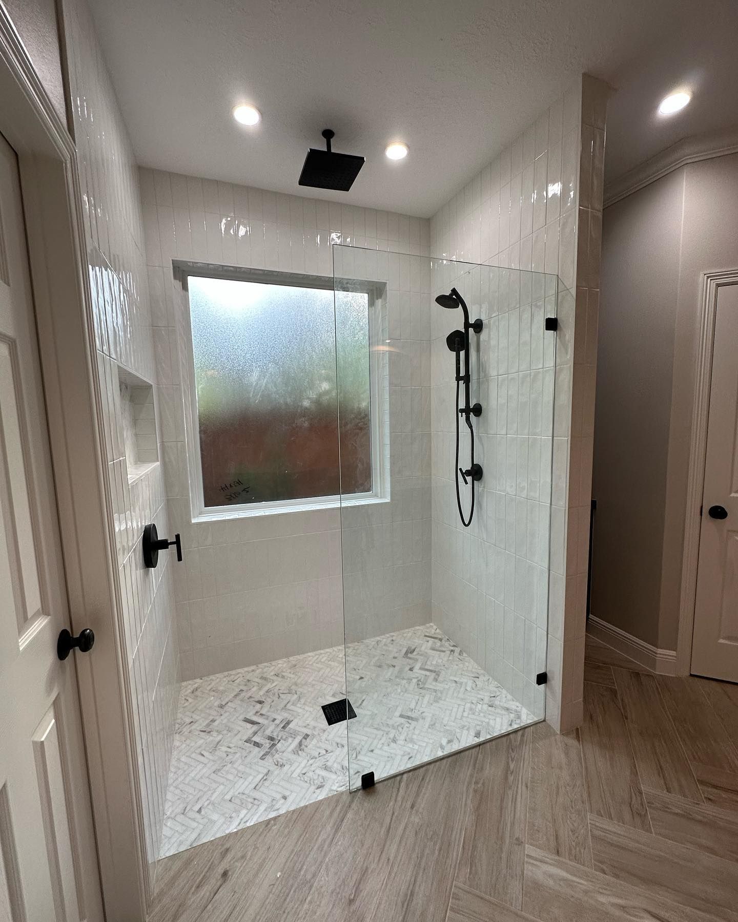 A bathroom with a walk in shower and a window.