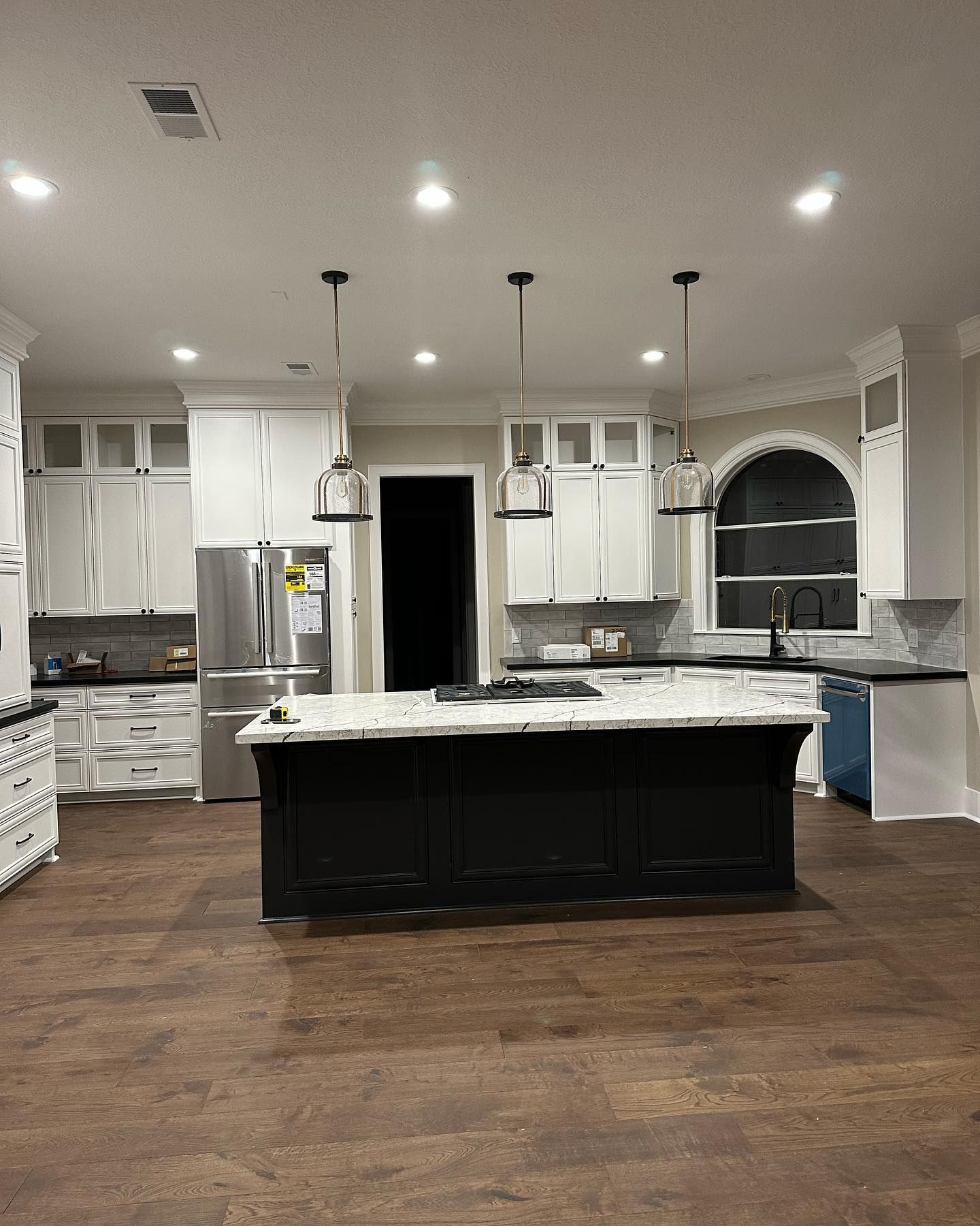 A kitchen with white cabinets and a black island