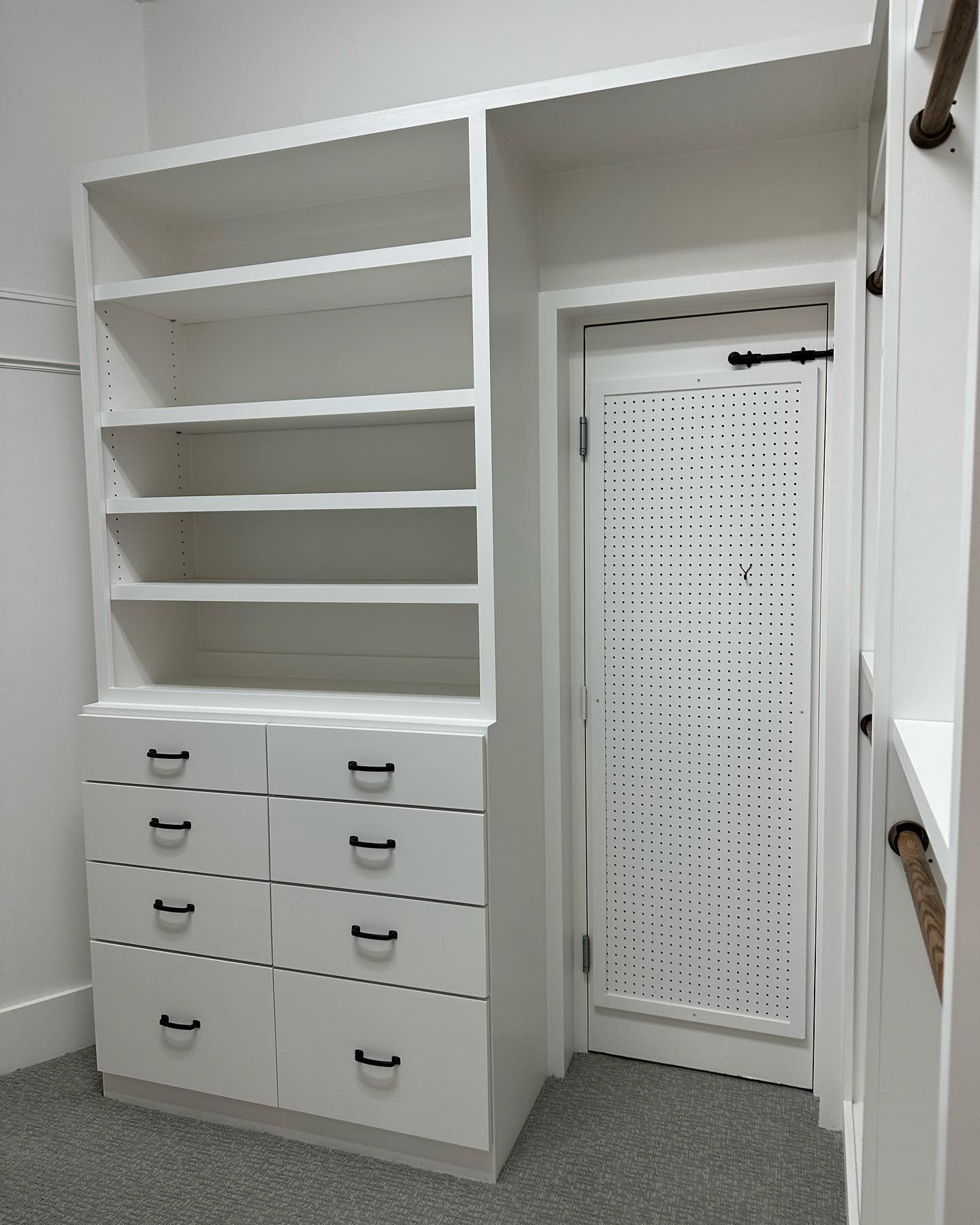 A walk in closet with shelves and drawers and a door.