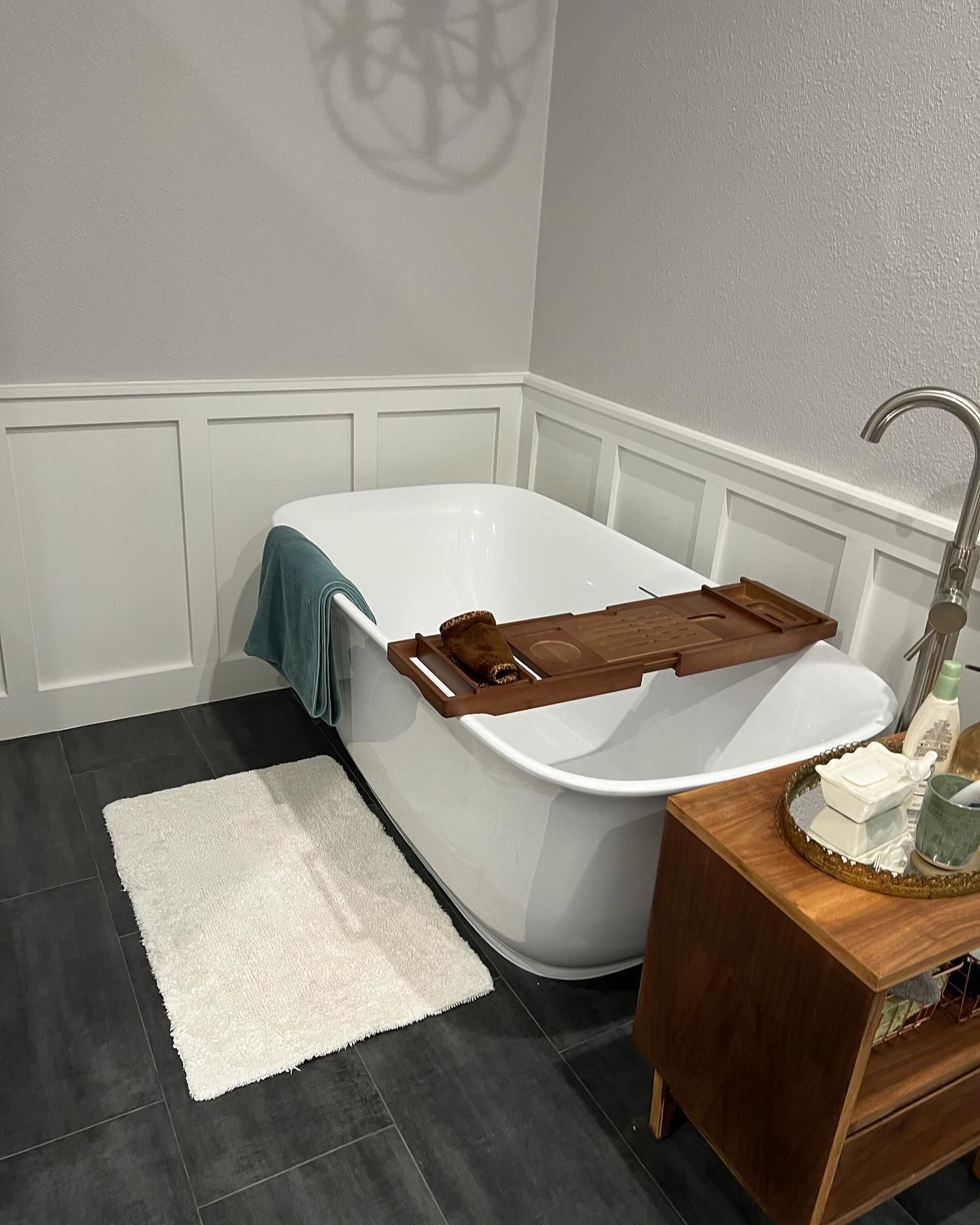 A bathtub with a wooden tray on top of it in a bathroom.