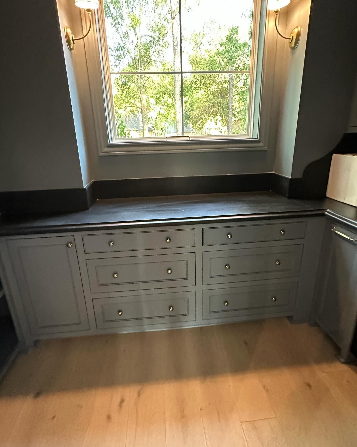 A kitchen with gray cabinets and drawers under a window.
