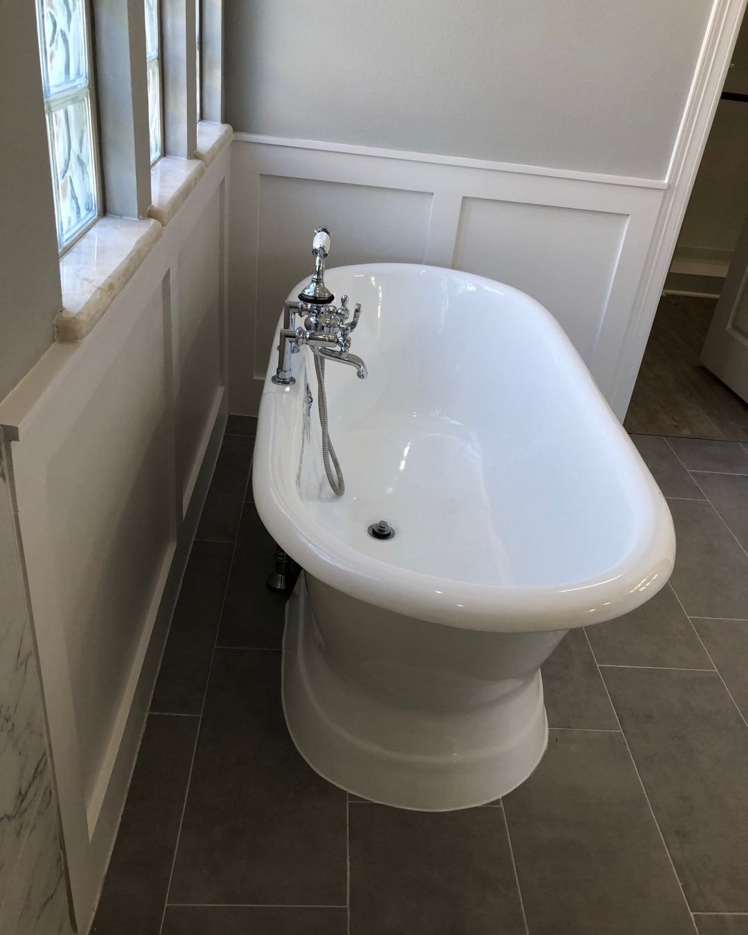 A white bathtub is sitting in a bathroom next to a window.