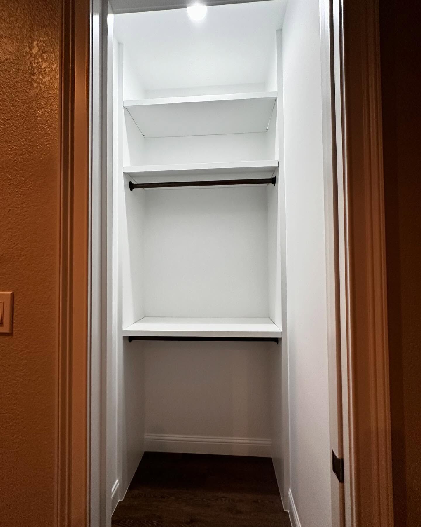 An empty closet with shelves and a hanging bar