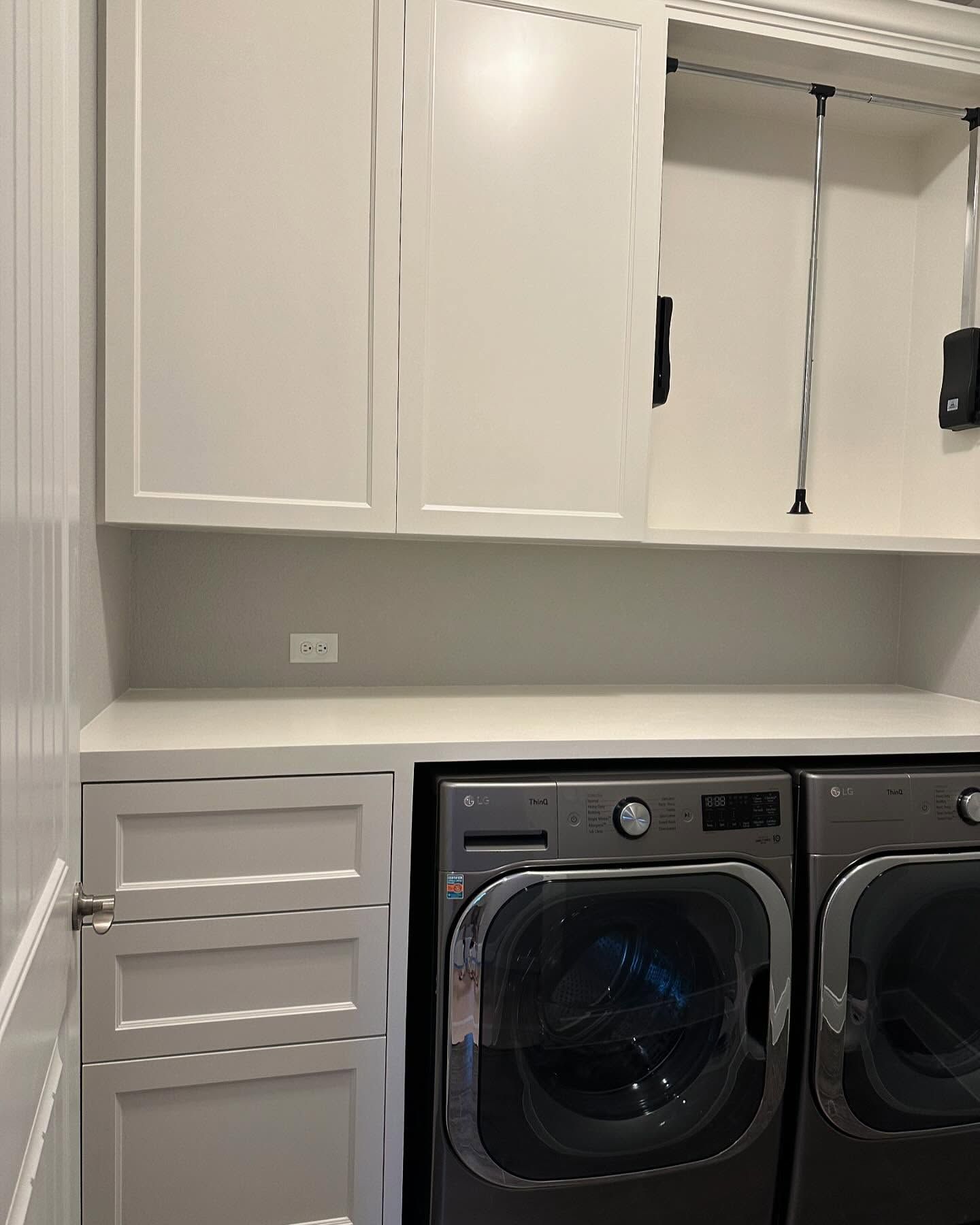 A laundry room with a washer and dryer and white cabinets.