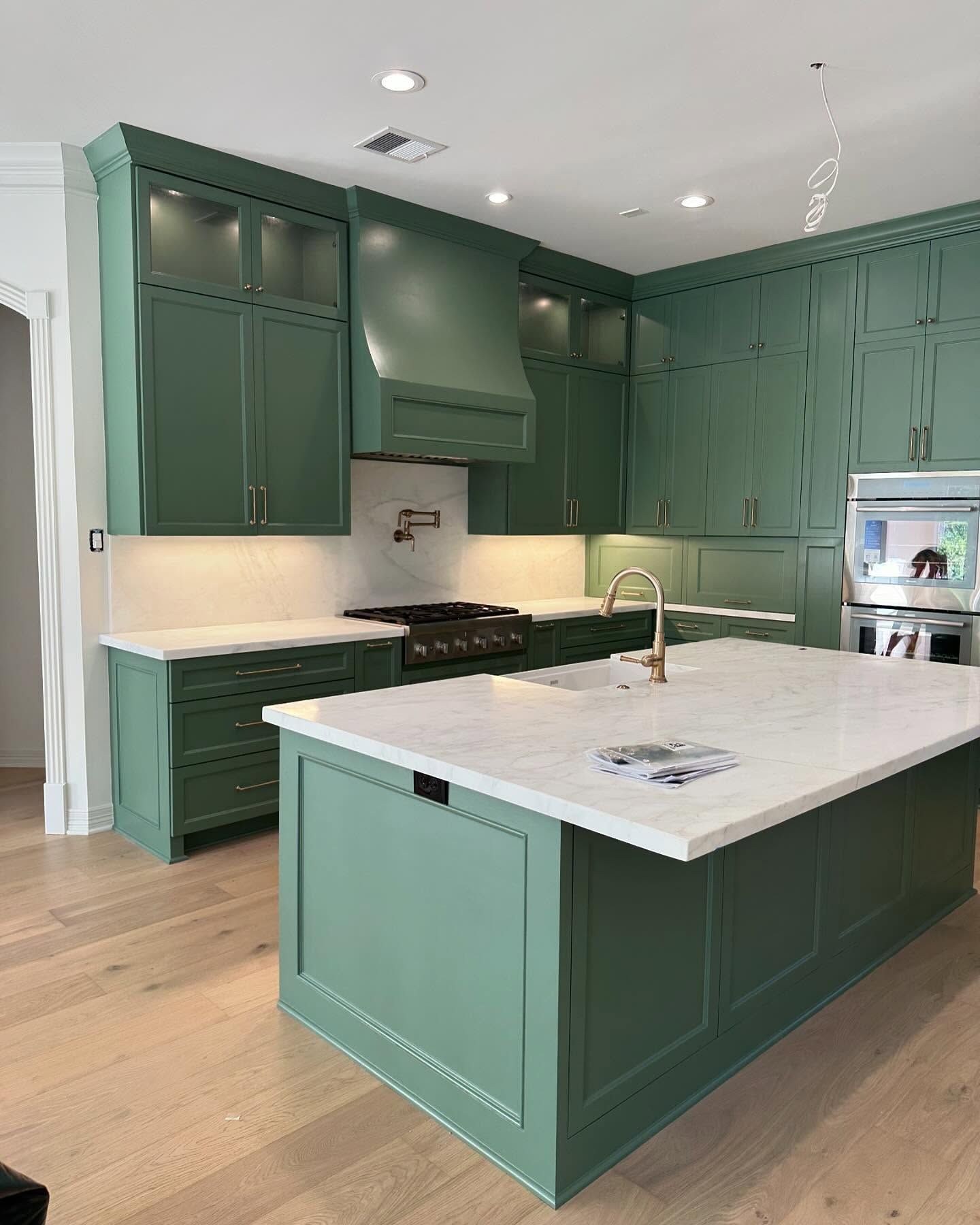 A kitchen with green cabinets and a large island.
