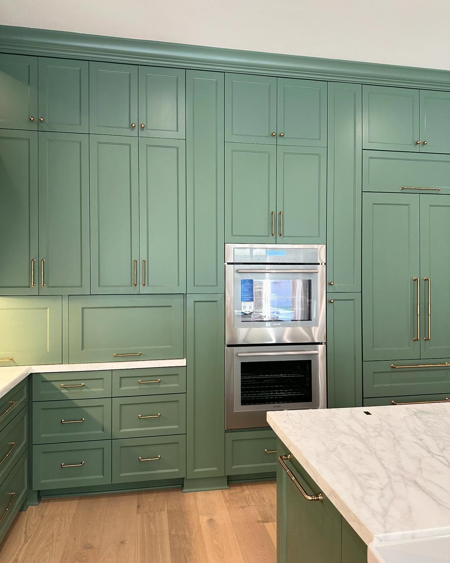 A kitchen with green cabinets and a stainless steel oven