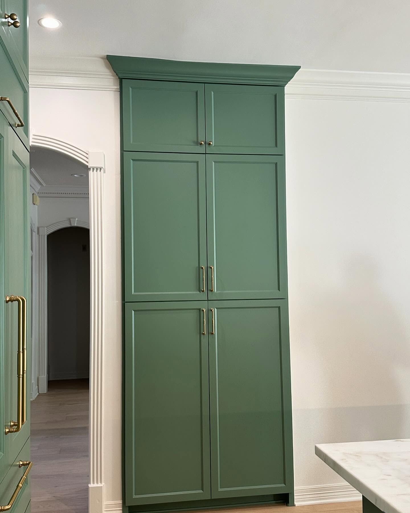 A kitchen with green cabinets and a marble counter top.