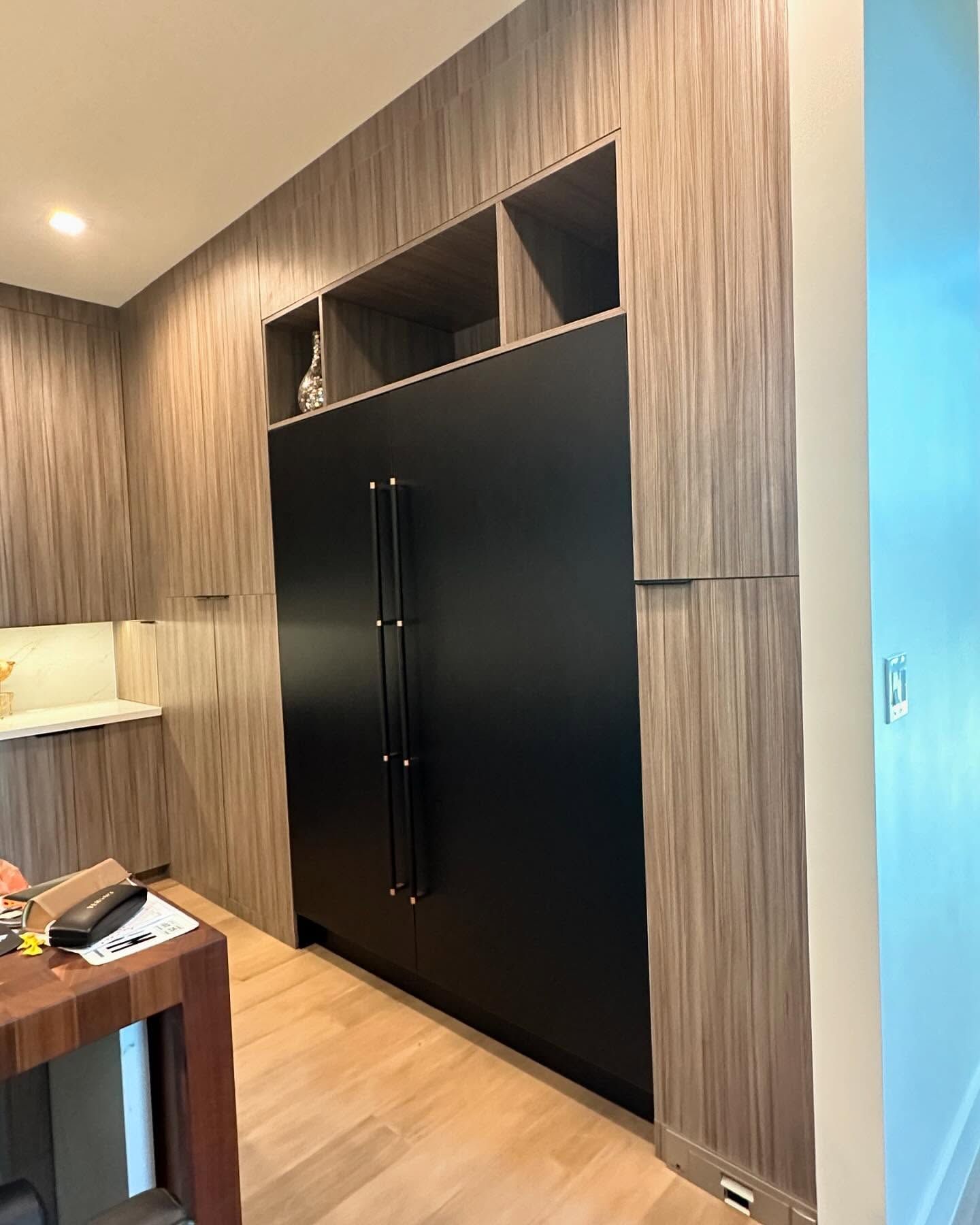 A kitchen with wooden cabinets and a black refrigerator.