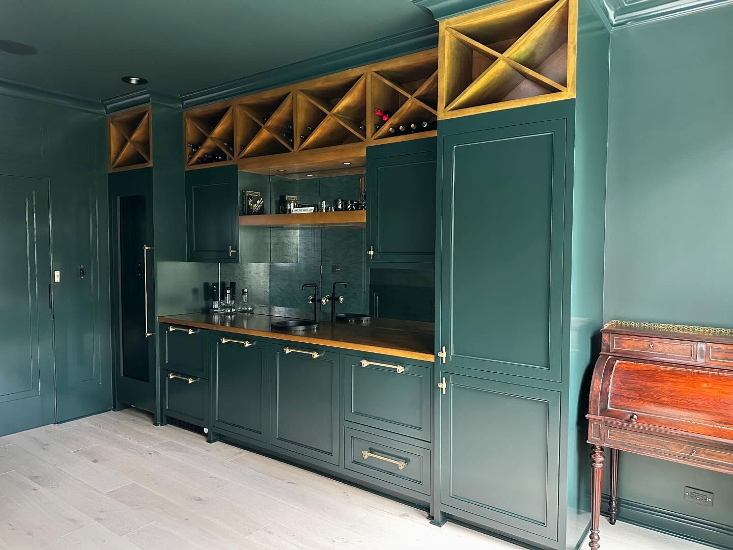 A kitchen with green cabinets and wooden counter tops.