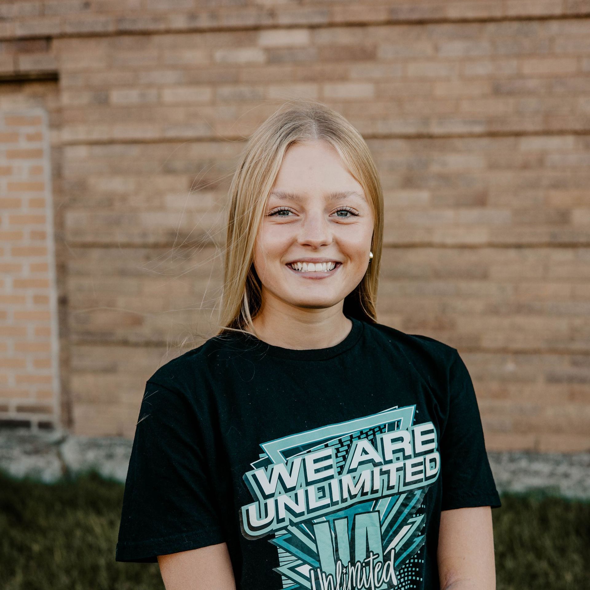 A young woman is sitting on a wooden box with her legs crossed.