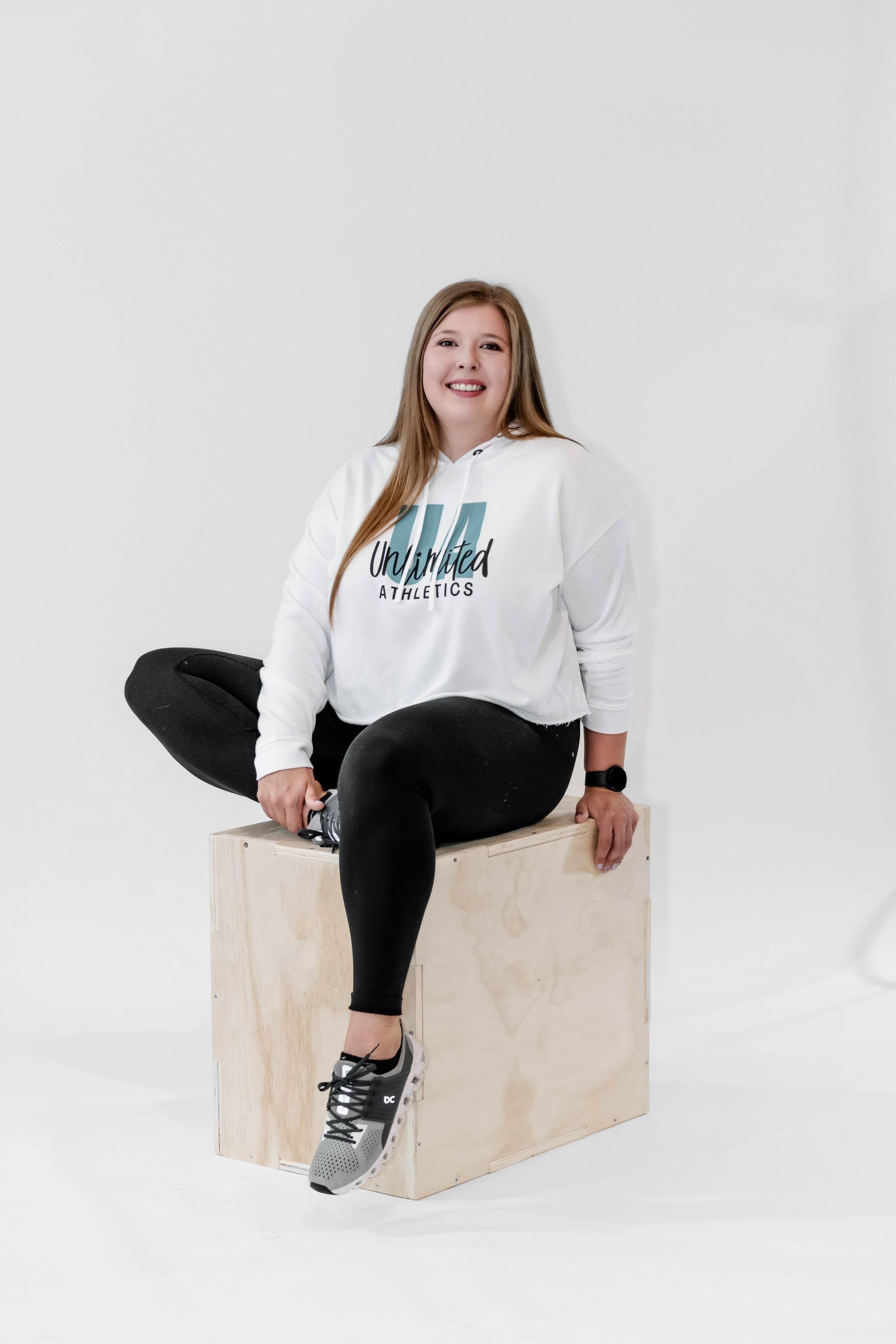 A woman is sitting on a wooden box with her legs crossed.