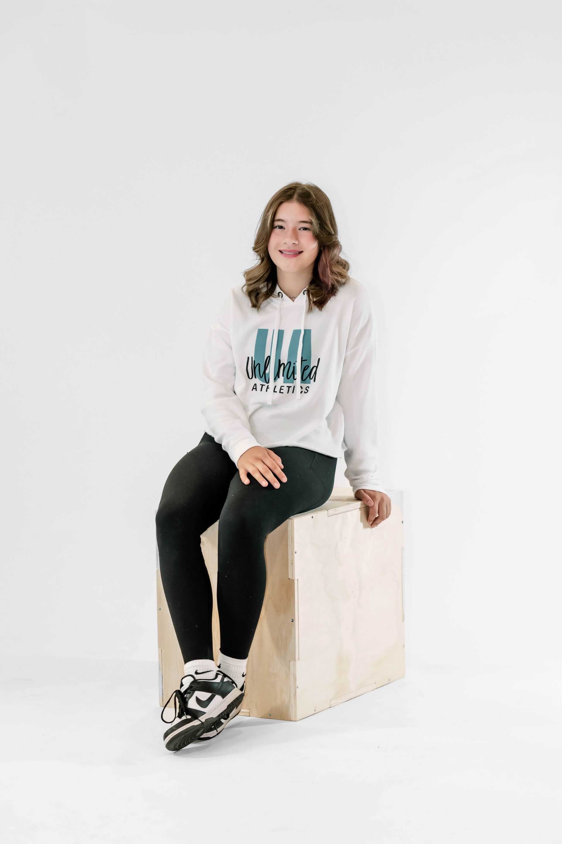 A young girl is sitting on a wooden box.