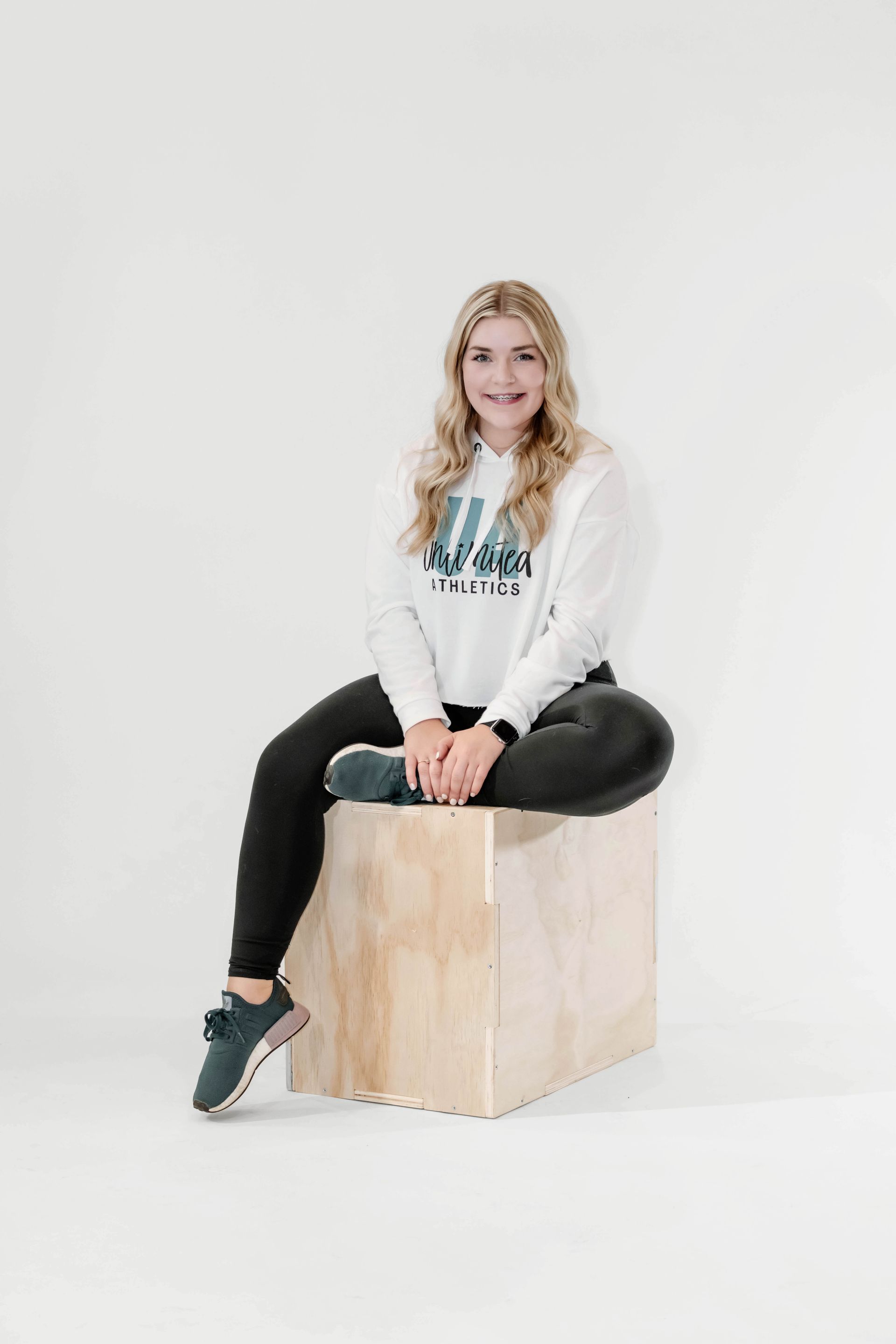 A woman is sitting on a wooden box with her legs crossed.