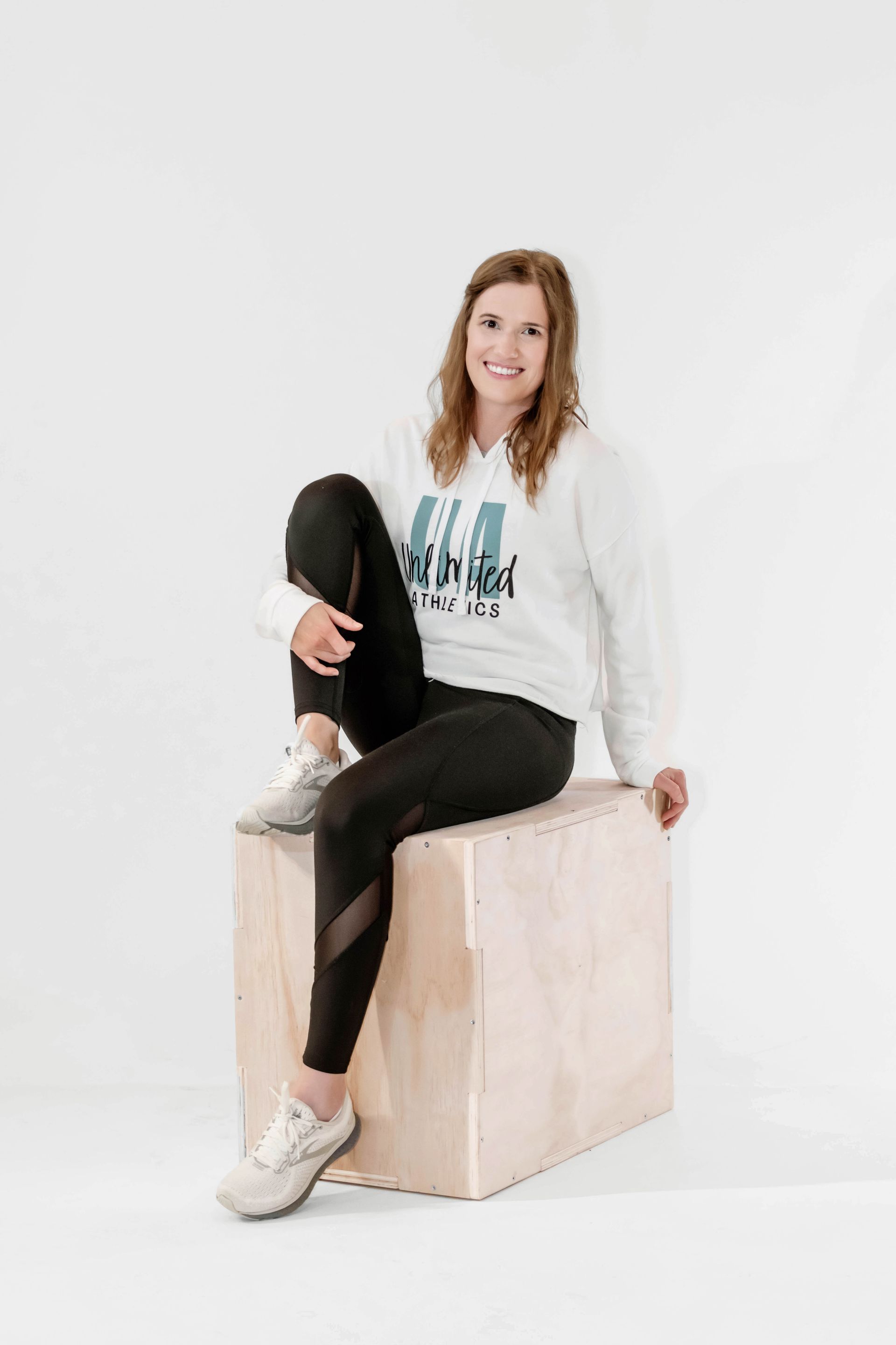 A woman is sitting on a wooden box with her legs crossed.