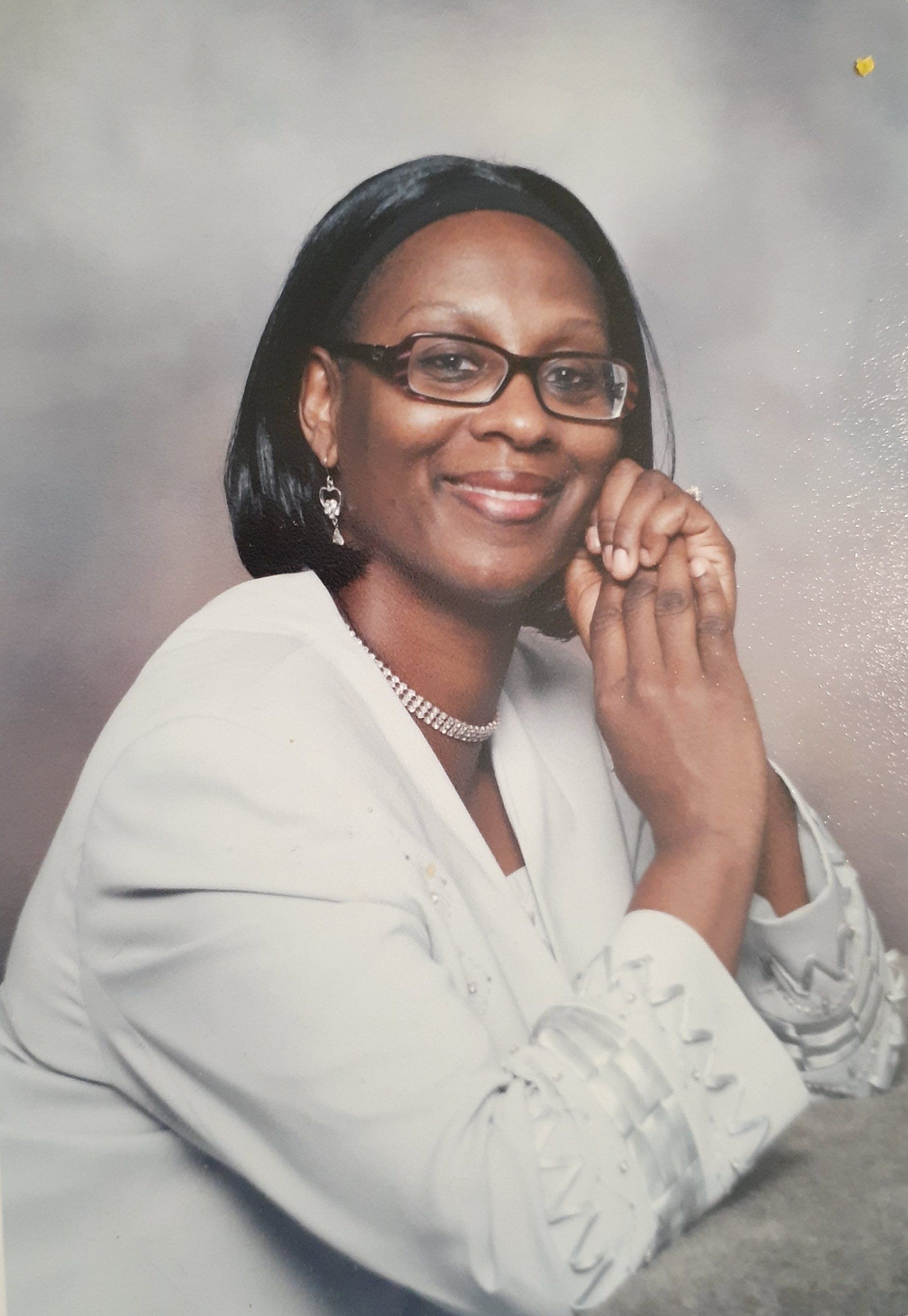 A woman wearing glasses and a white shirt is posing for a picture.