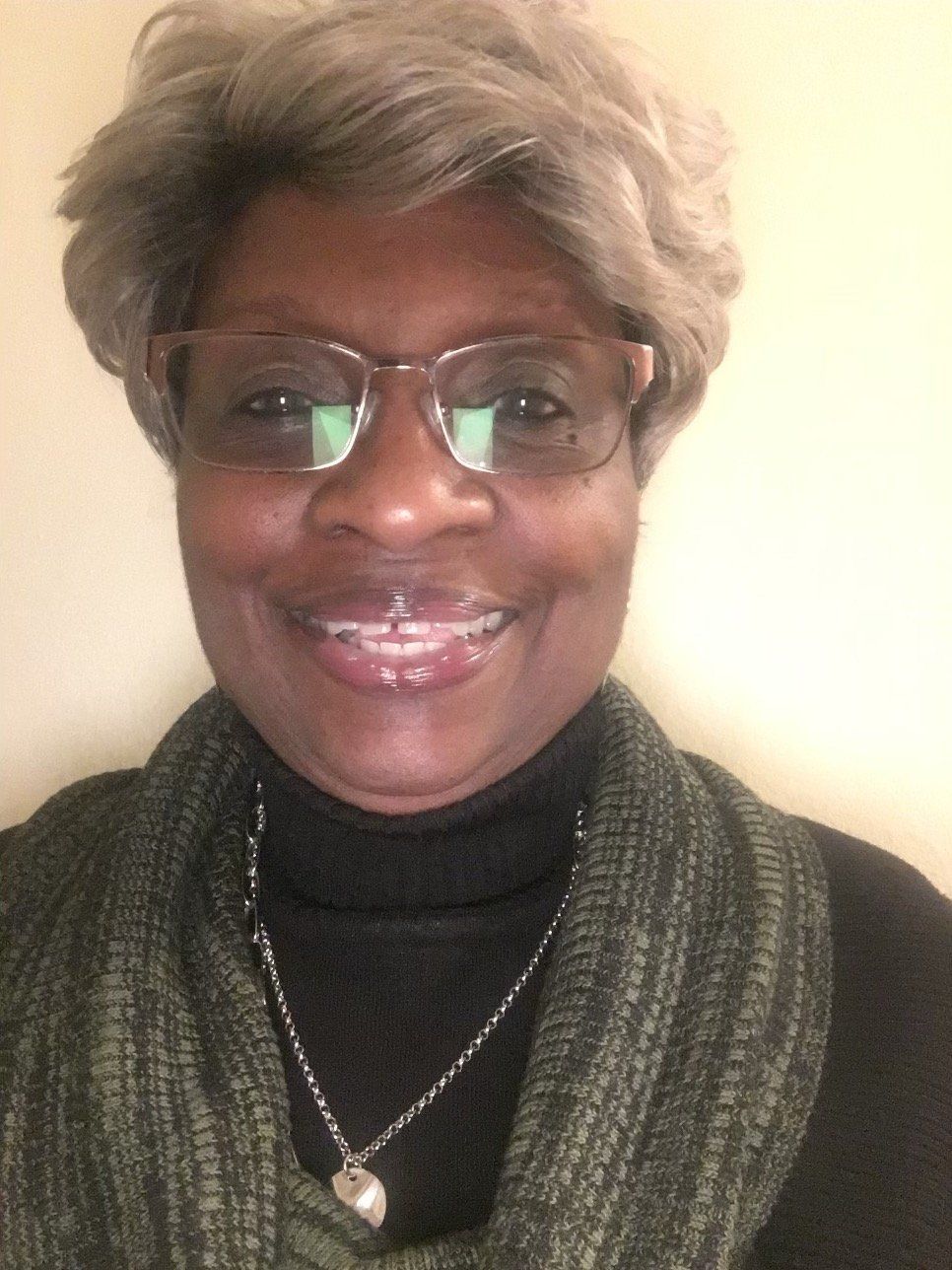 A woman wearing glasses and a scarf is smiling for the camera.