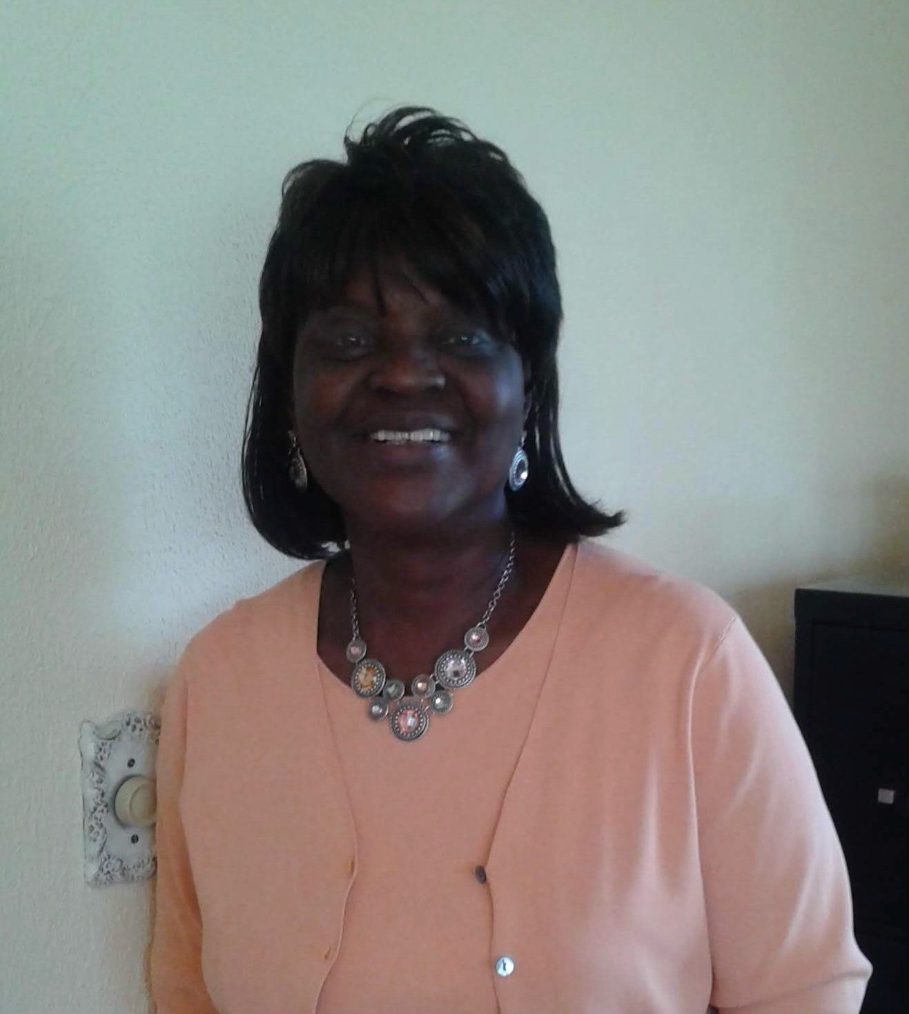 A woman wearing a necklace and earrings smiles for the camera