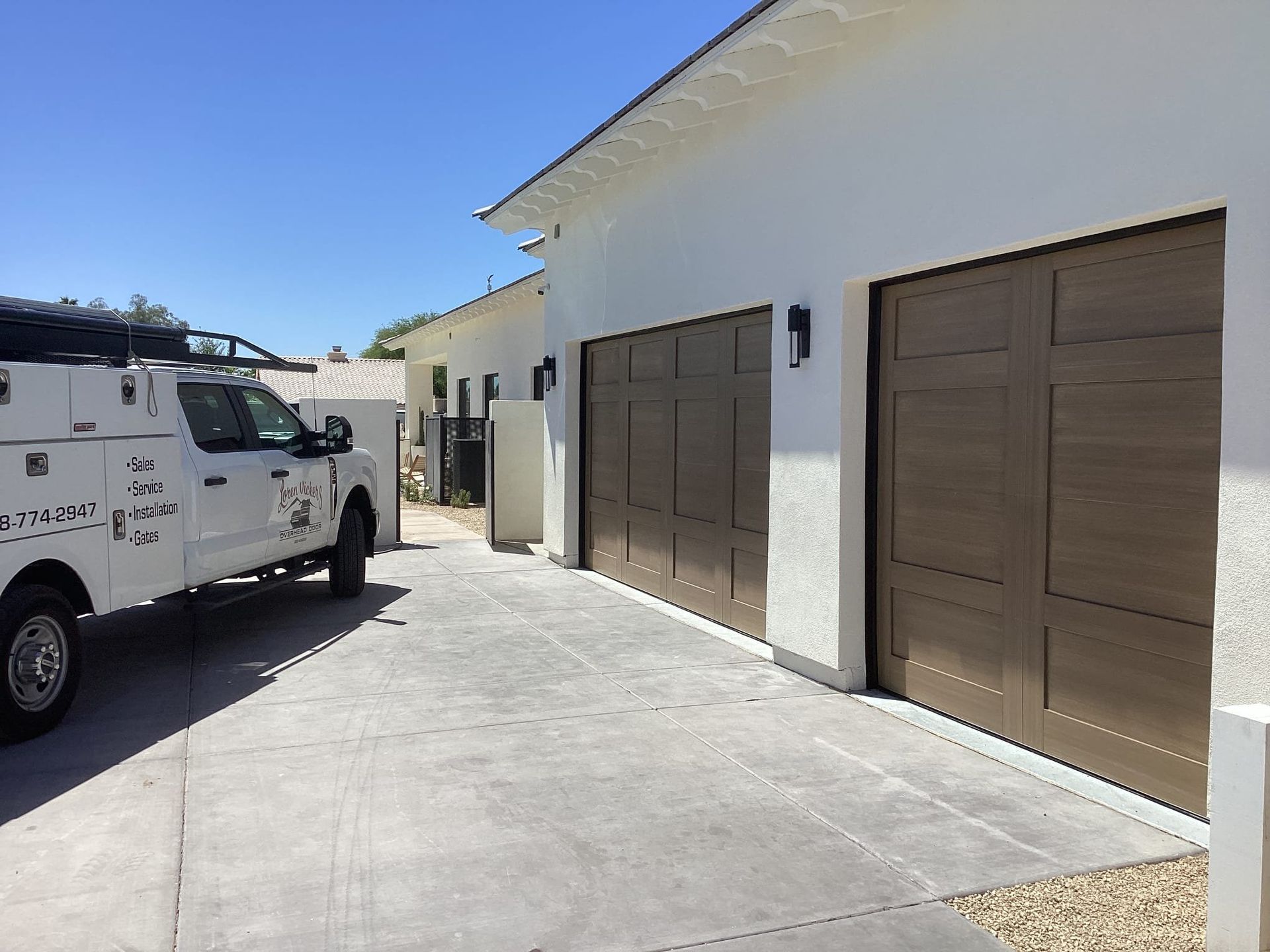 A white truck is parked in front of a garage door.