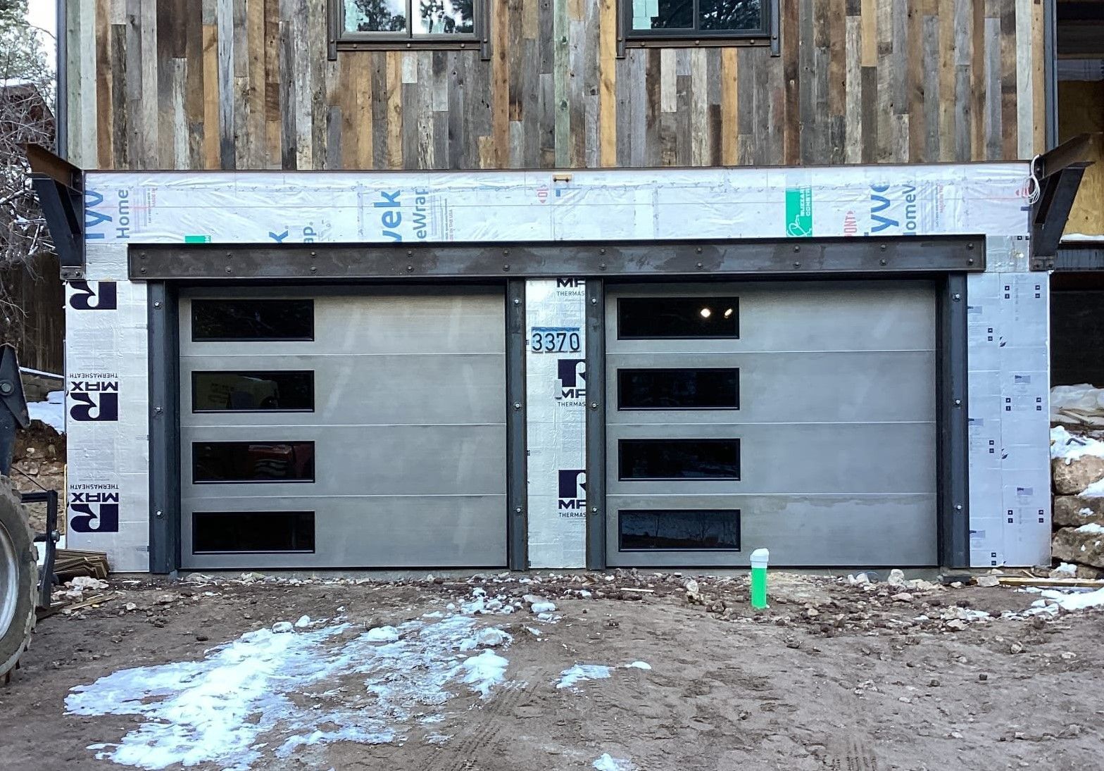 A garage door is being installed in front of a wooden house