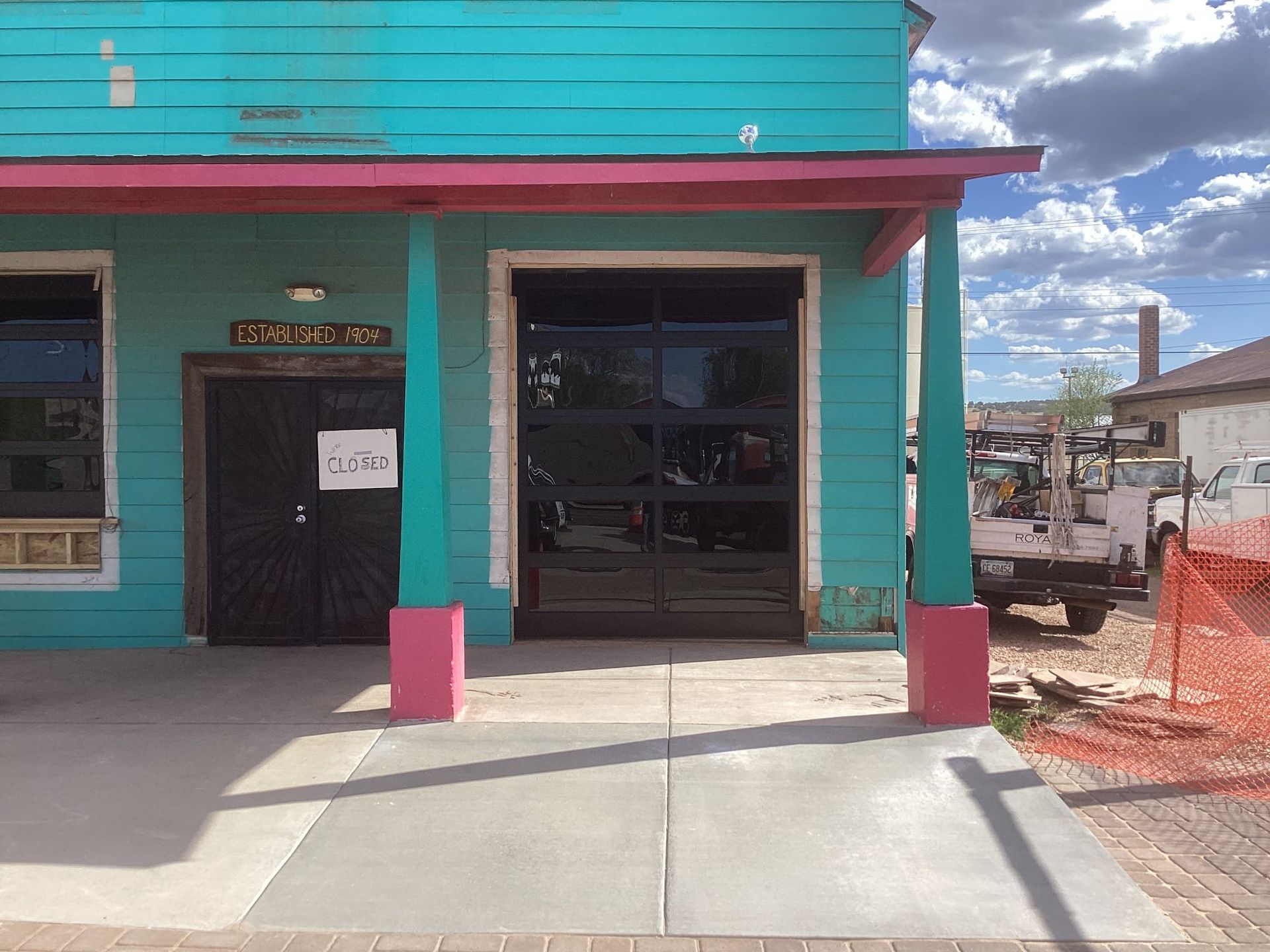 A blue building with a pink porch and a garage door.