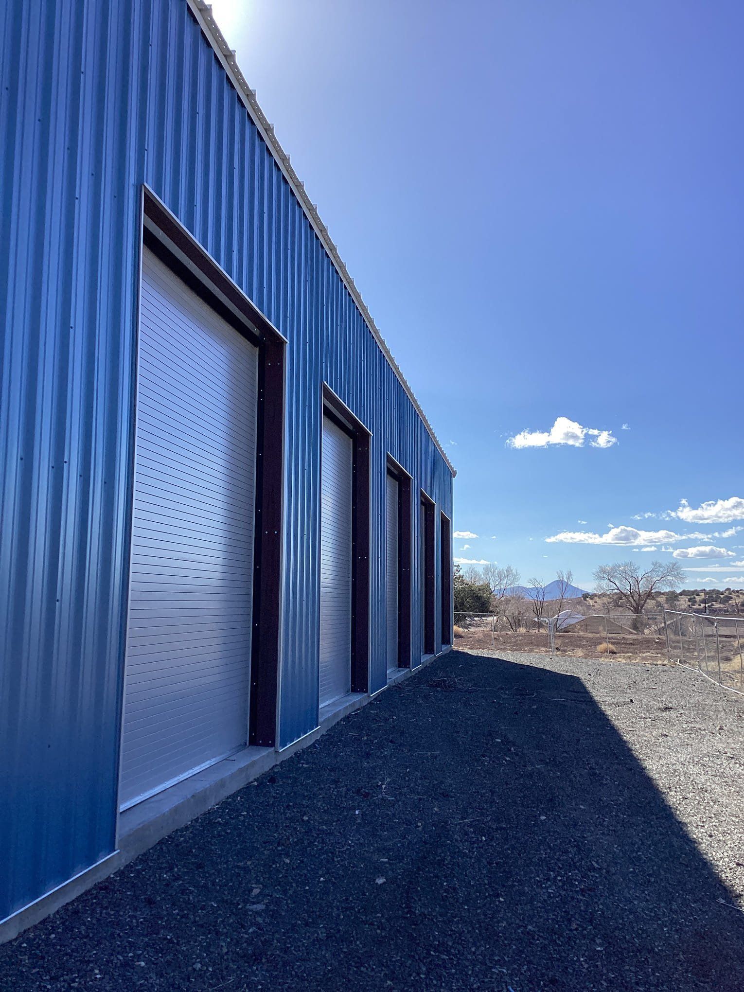A blue building with white garage doors on a sunny day.