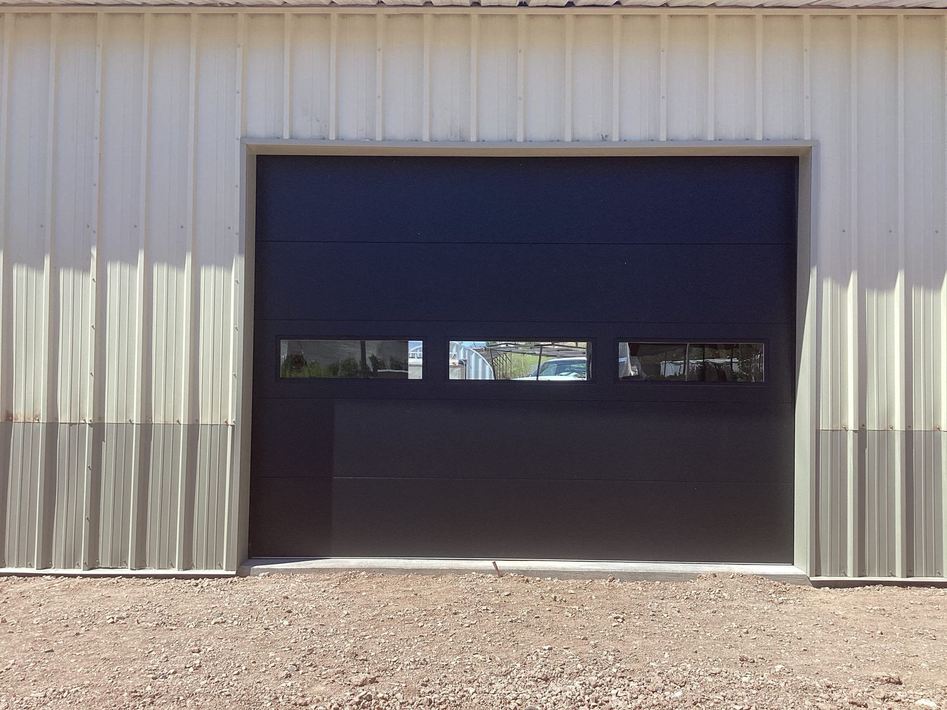 A black garage door is sitting in front of a white building.